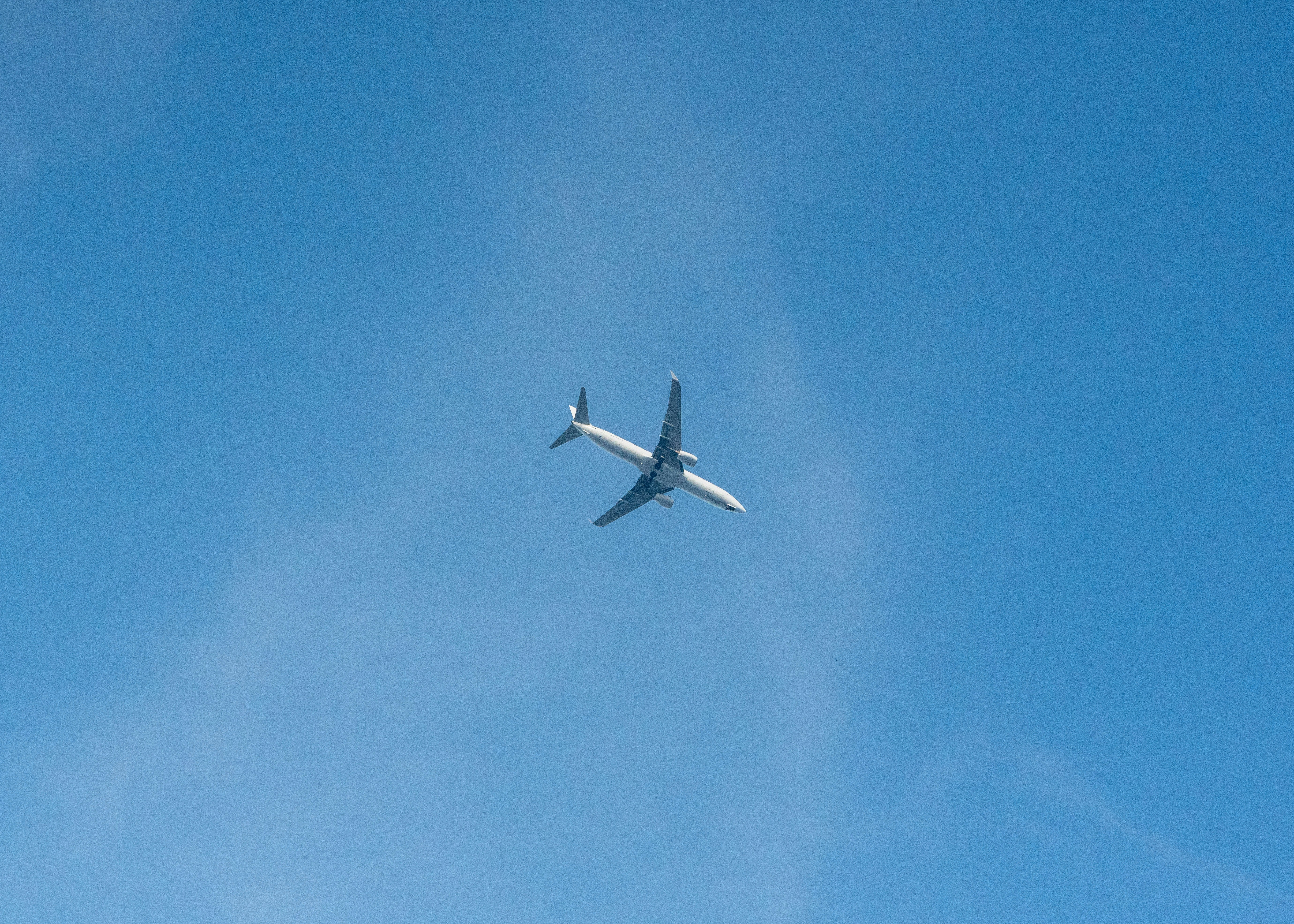 澄んだ青空を飛ぶ白い旅客機