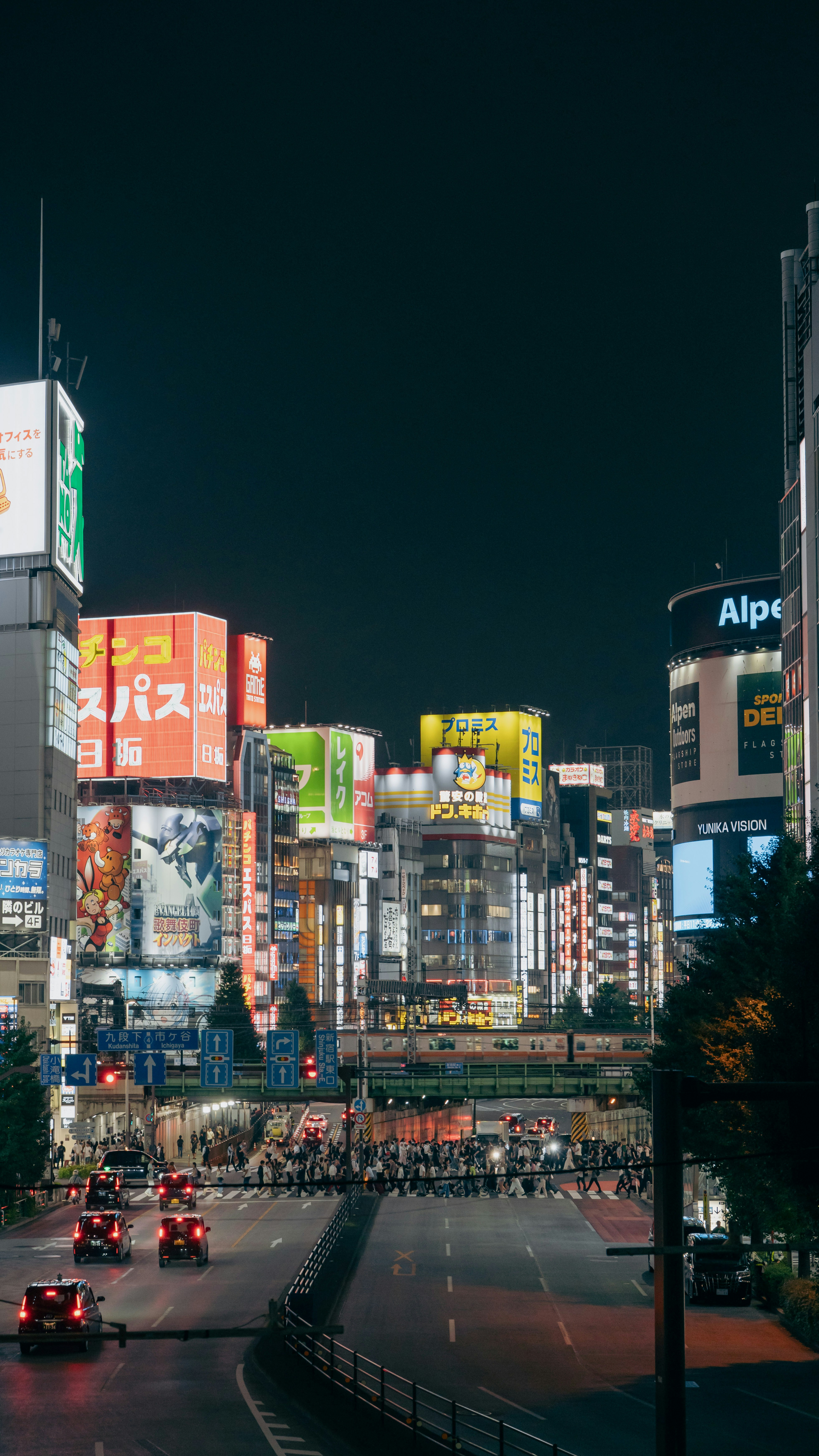 新宿の夜の賑やかな交差点、ネオンサインと交通が灯る