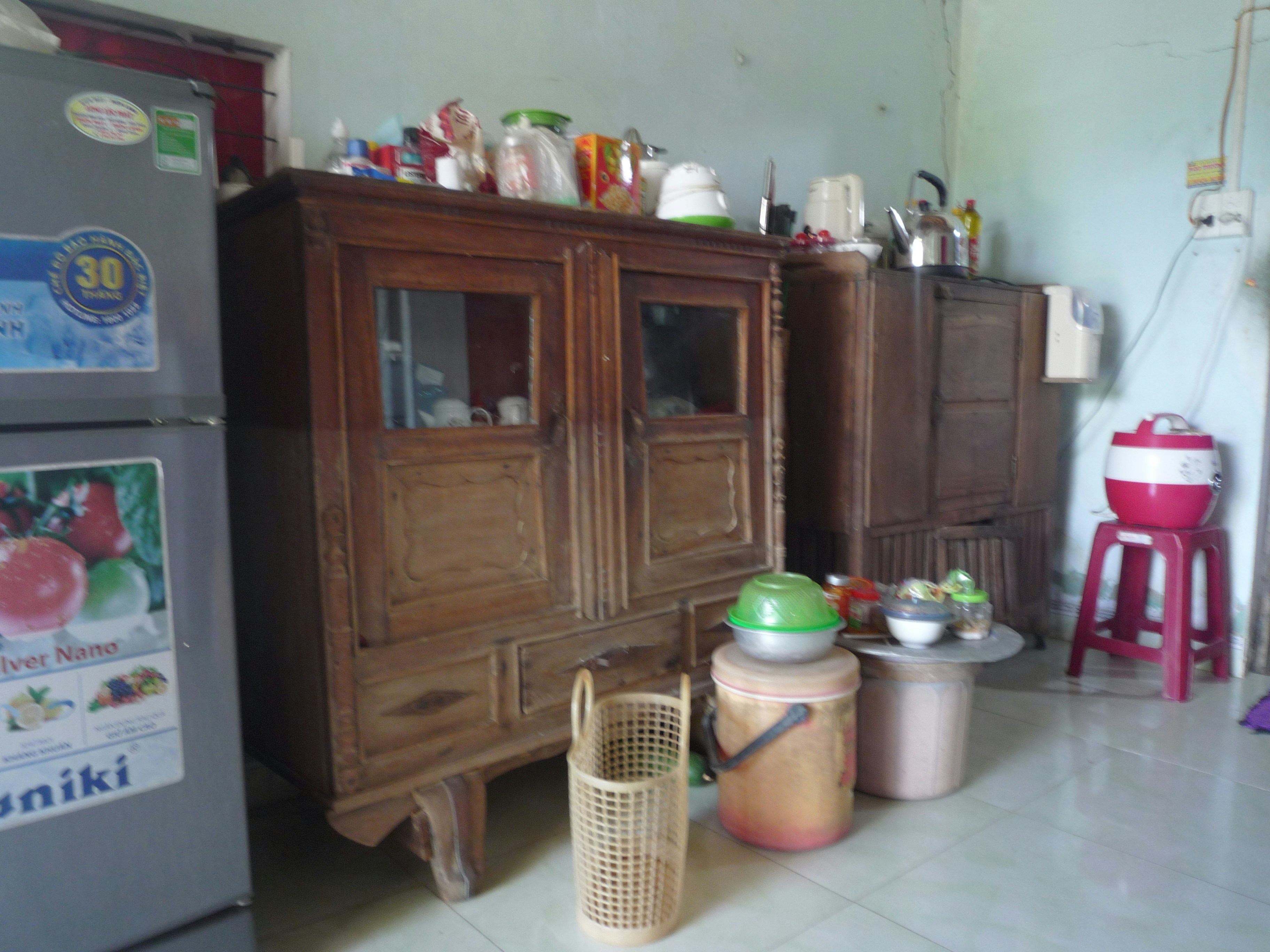 A wooden cabinet and kitchen appliances in a room with a tiled floor