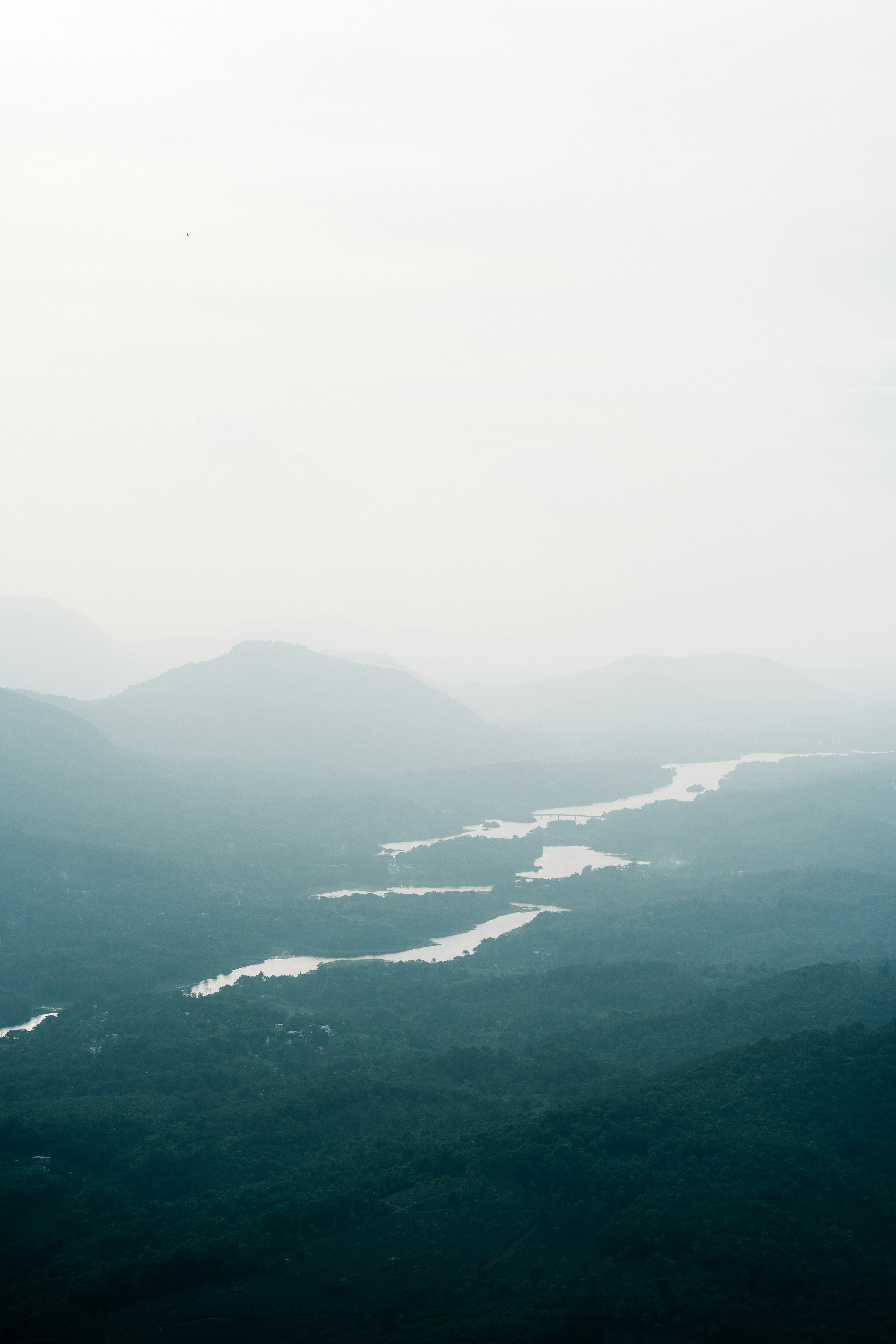 A winding river through a misty valley surrounded by forested mountains