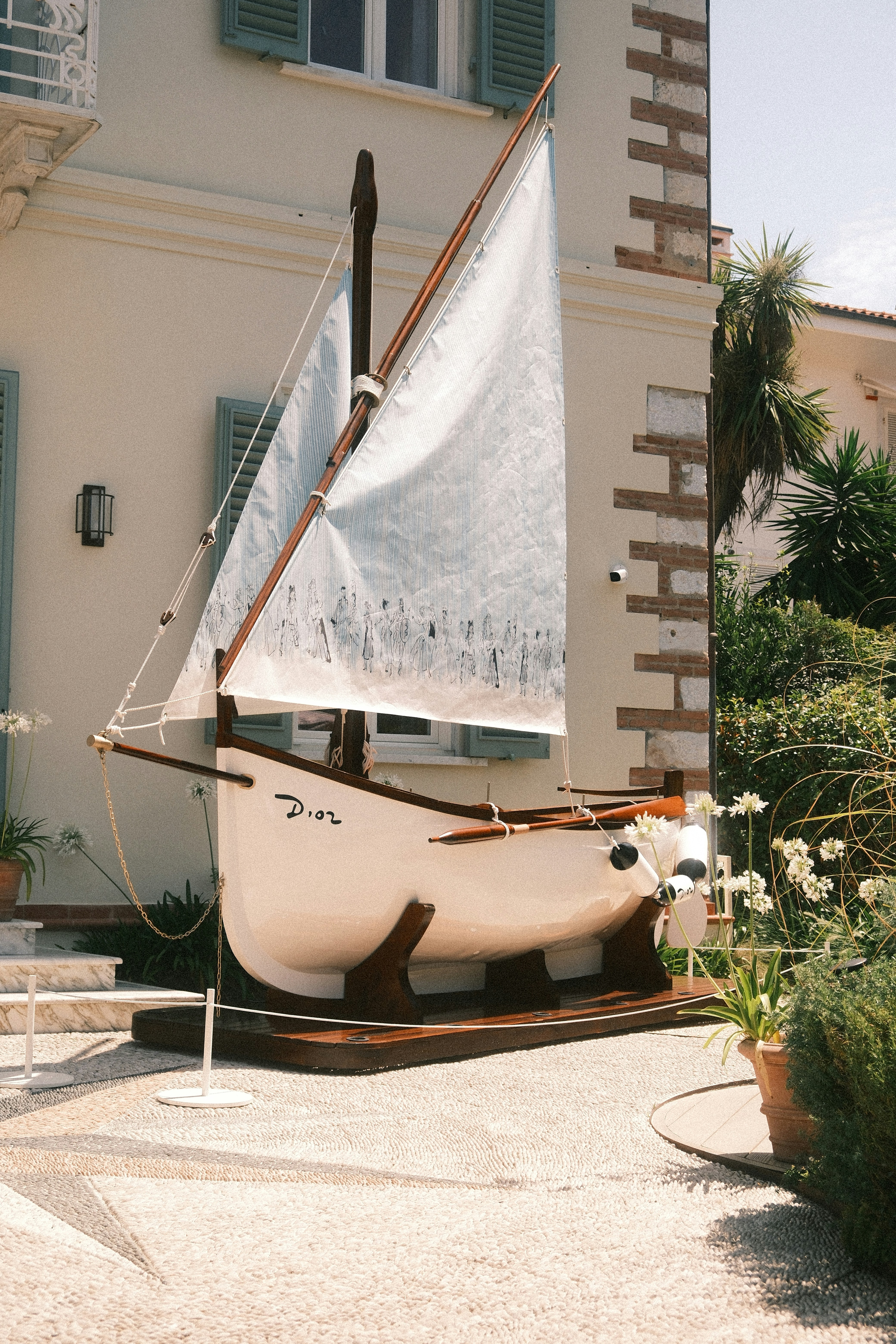 A small decorative sailboat model on a wooden stand in a garden