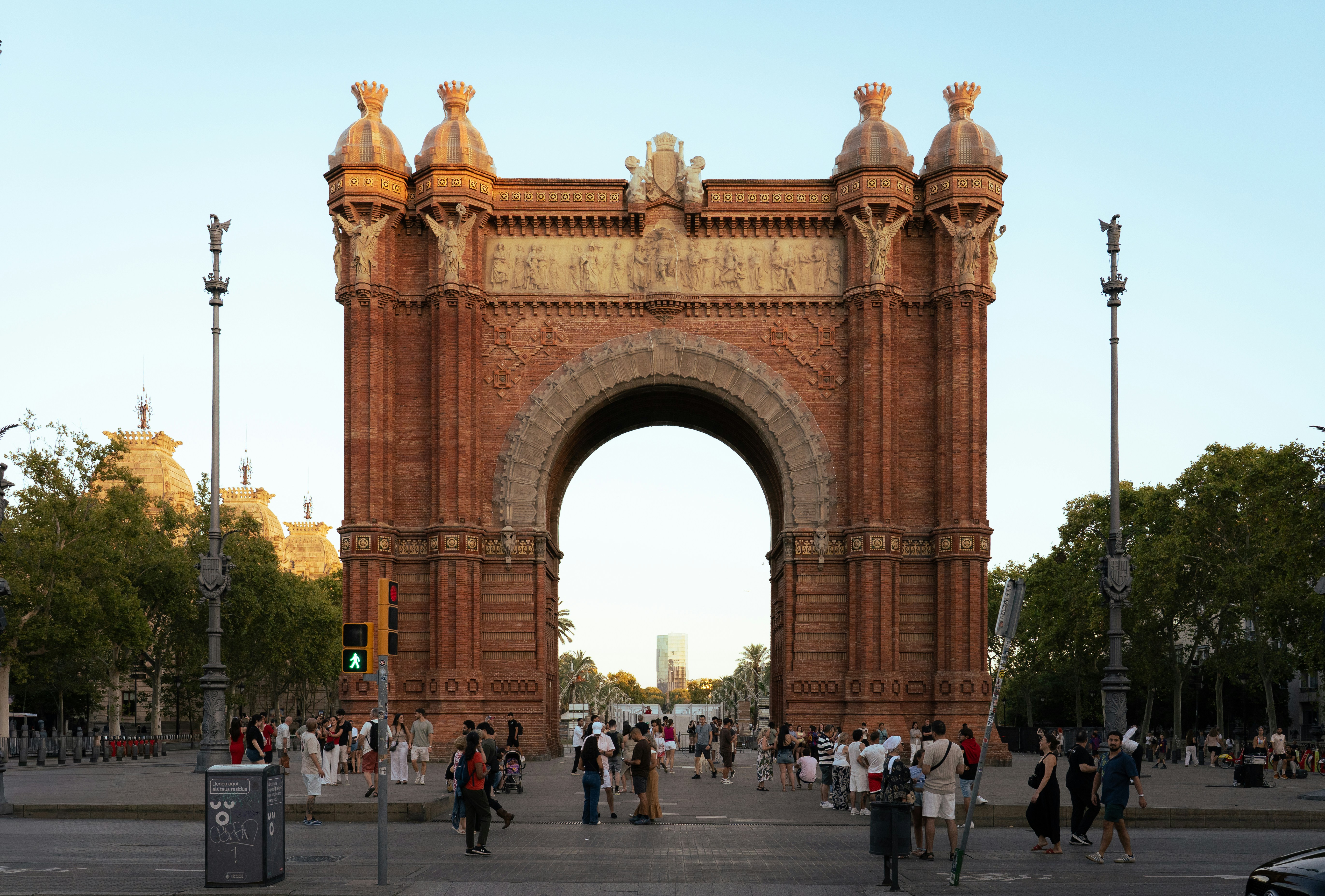 People walking in front of the Arc de Triomf in Barcelona at golden hour