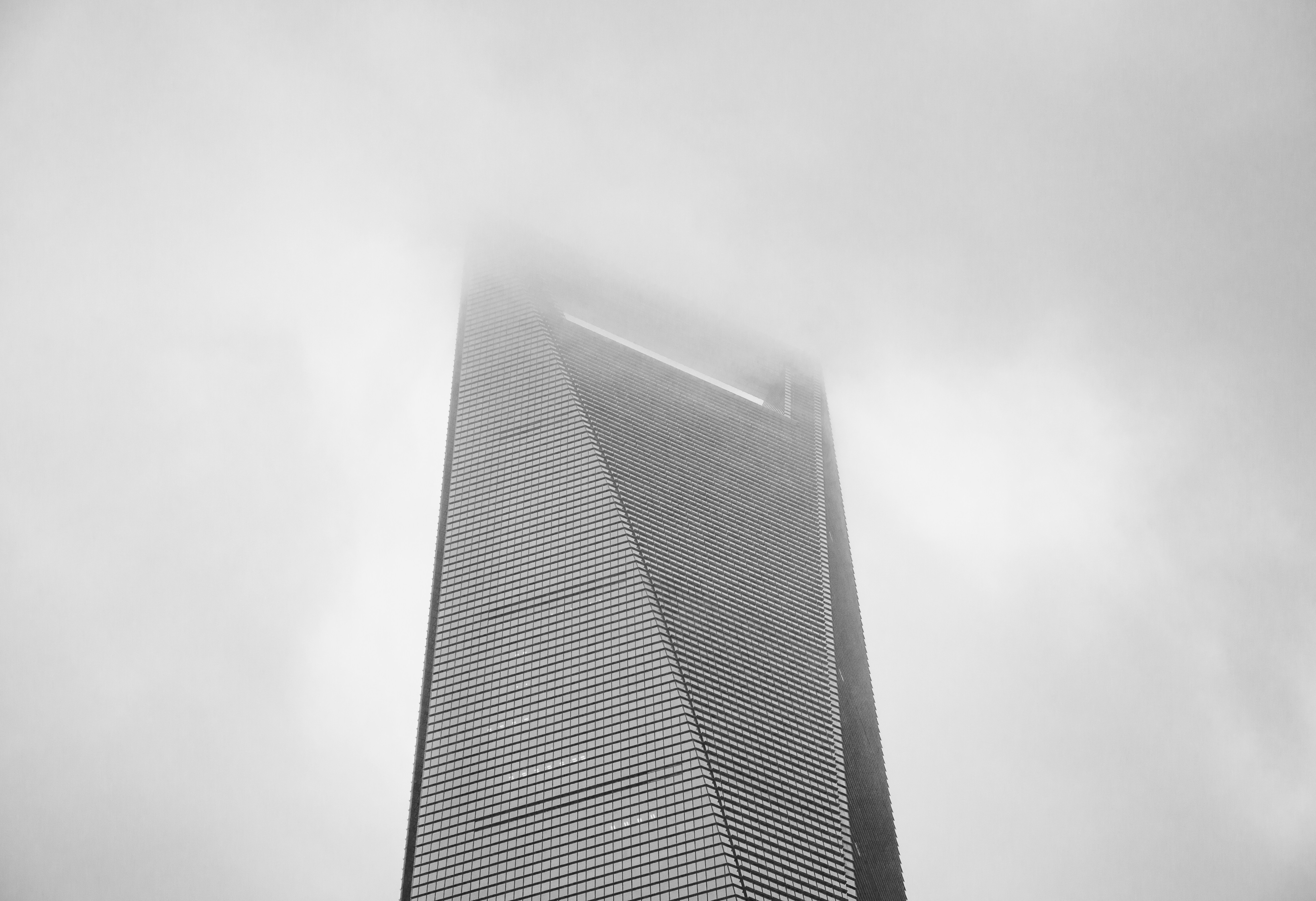 Un grattacielo moderno che si innalza in una fitta nebbia grigia e nuvole basse