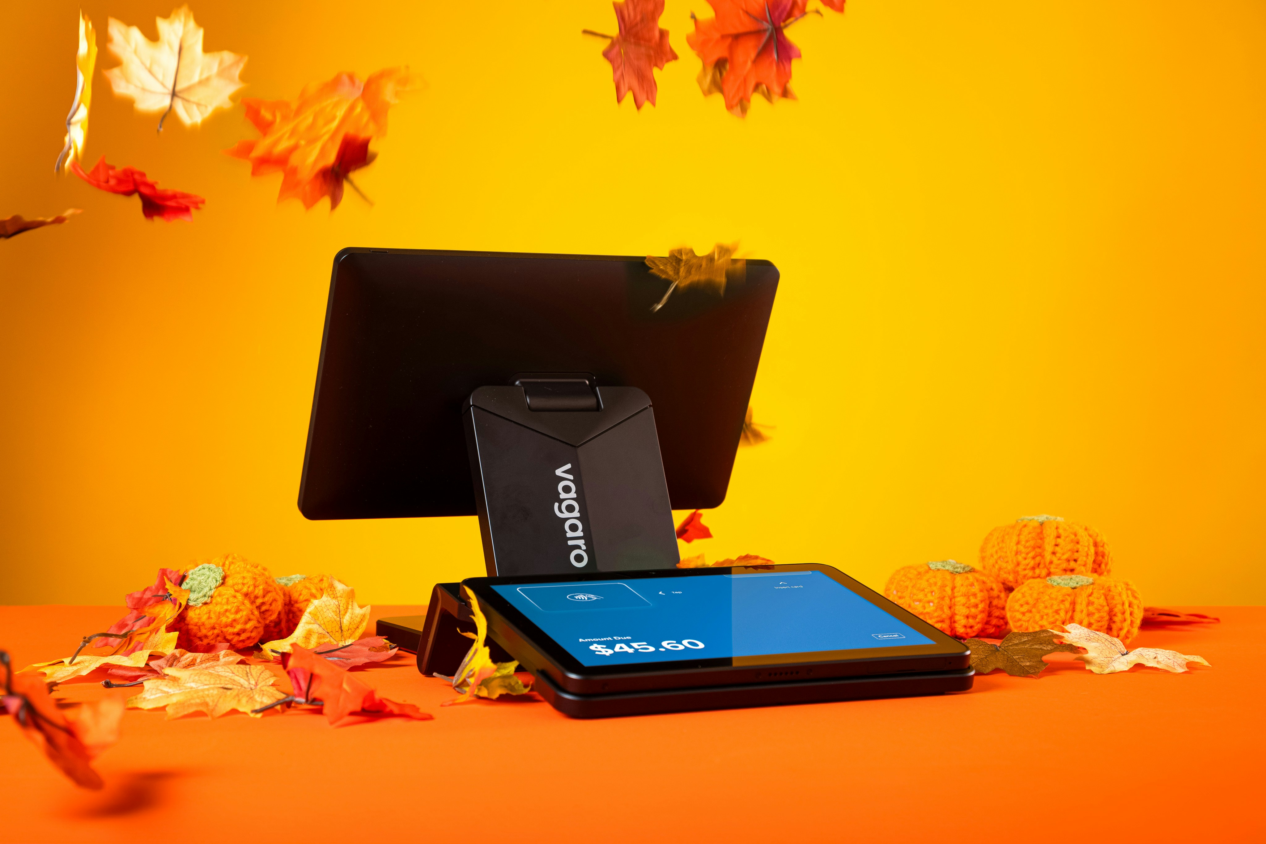 A point of sale terminal on an orange surface with autumn leaves and pumpkins