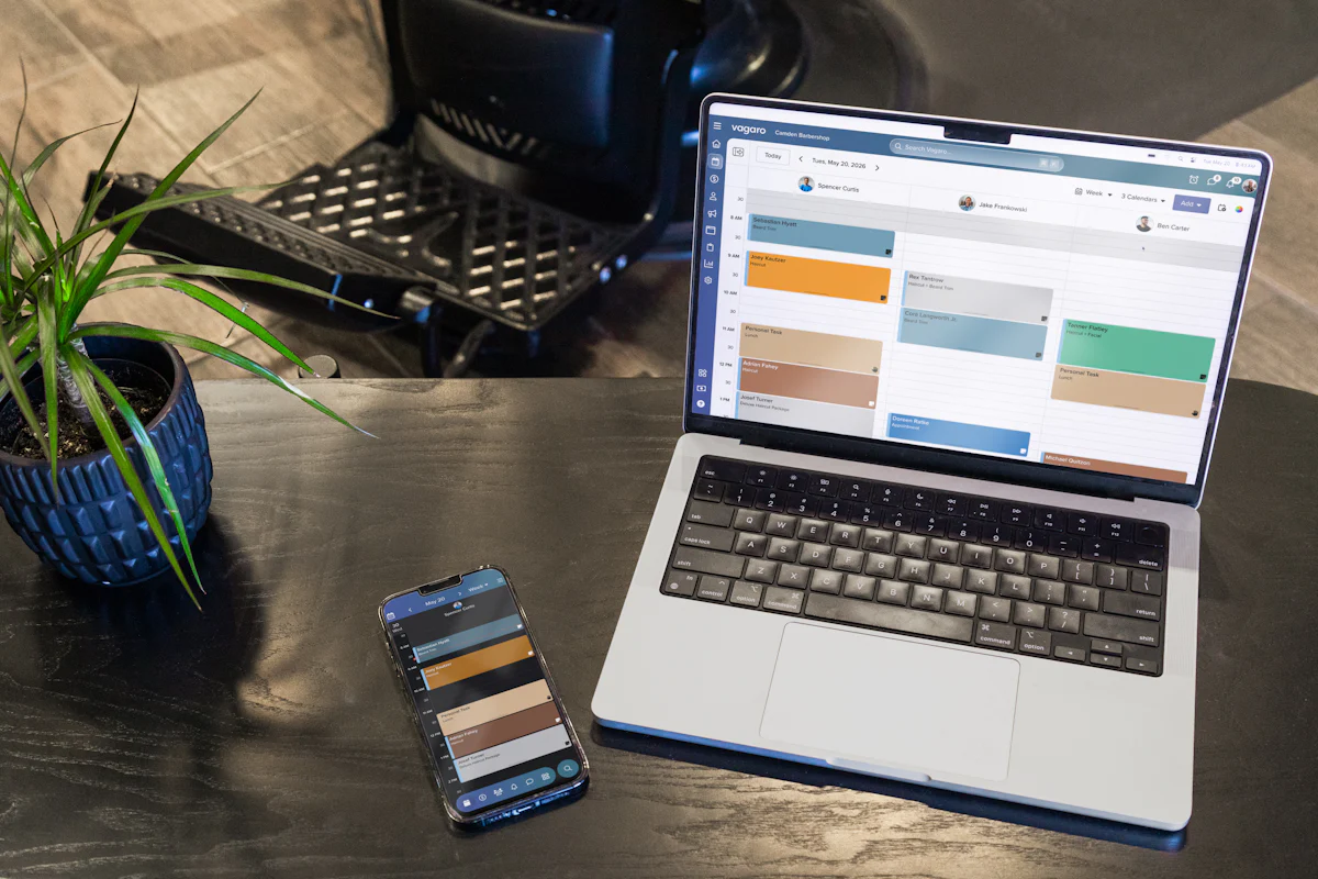 A laptop and a smartphone showing a booking calendar on a desk