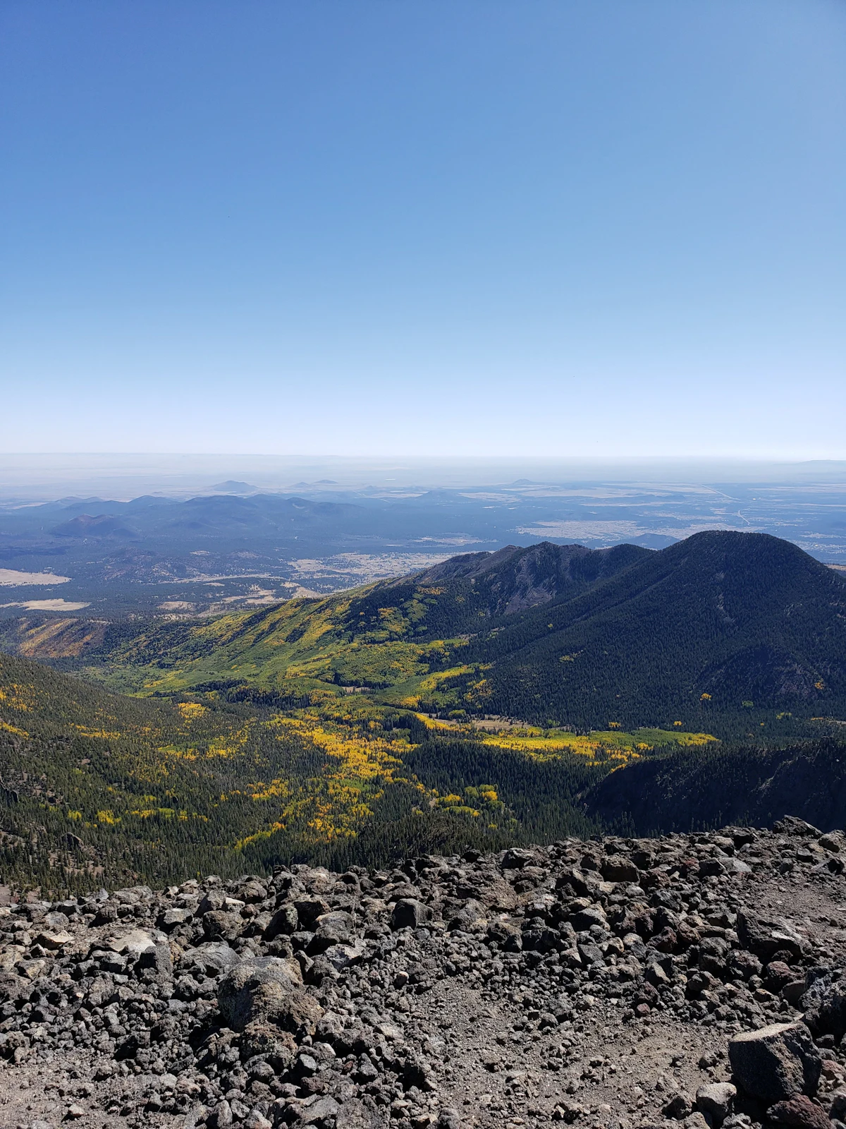 The view down from Humphreys Peak over yellow autumn trees and forested hills