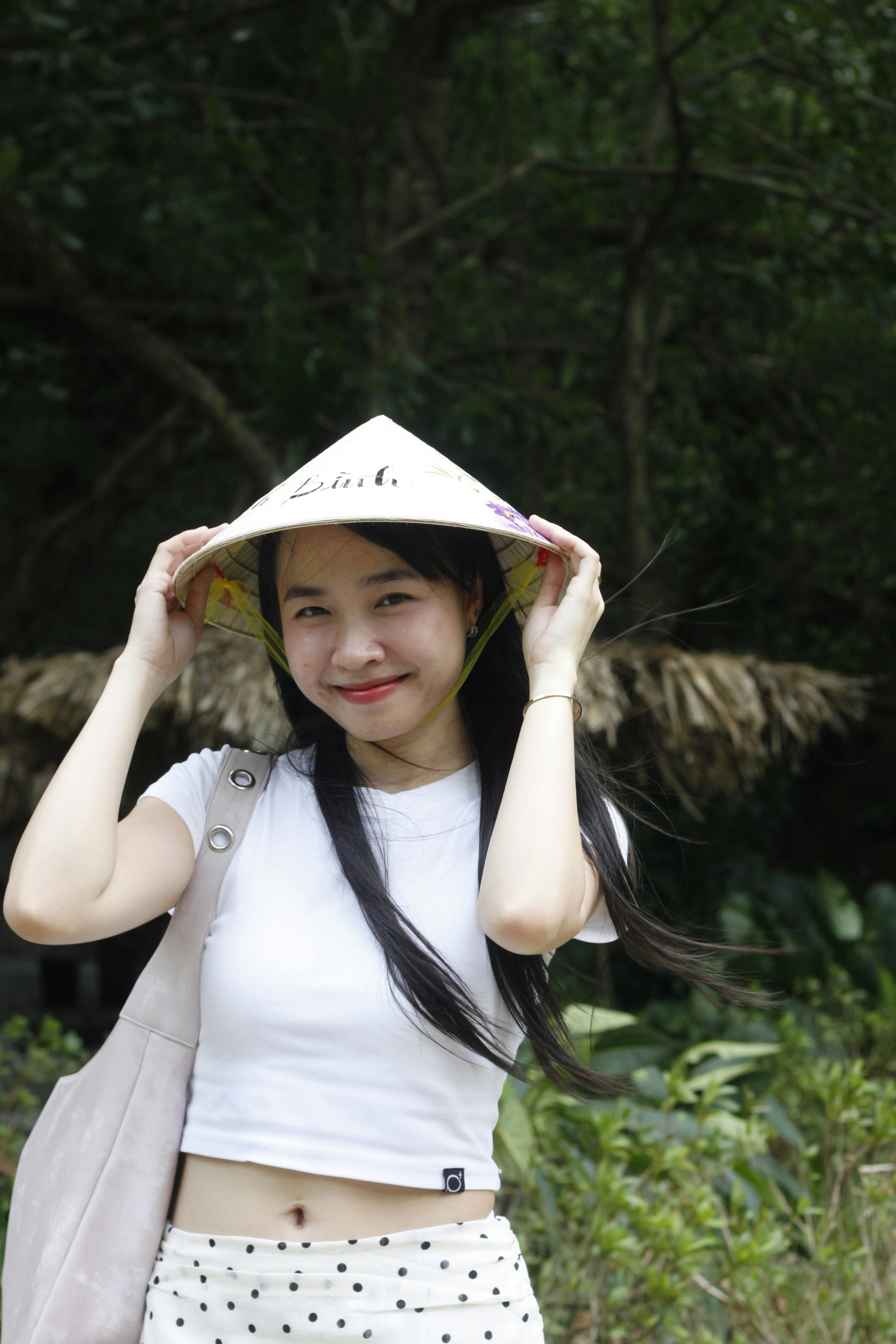 A woman in a white t-shirt wearing a conical hat in a garden