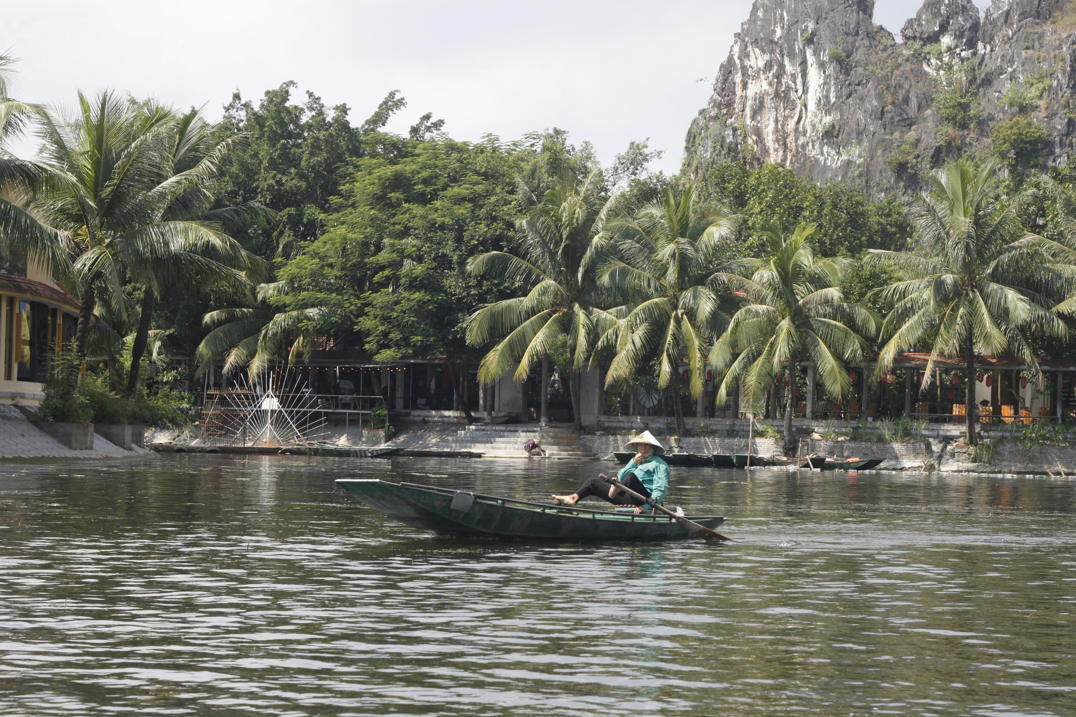 A person in a conical hat rowing a small boat on a river