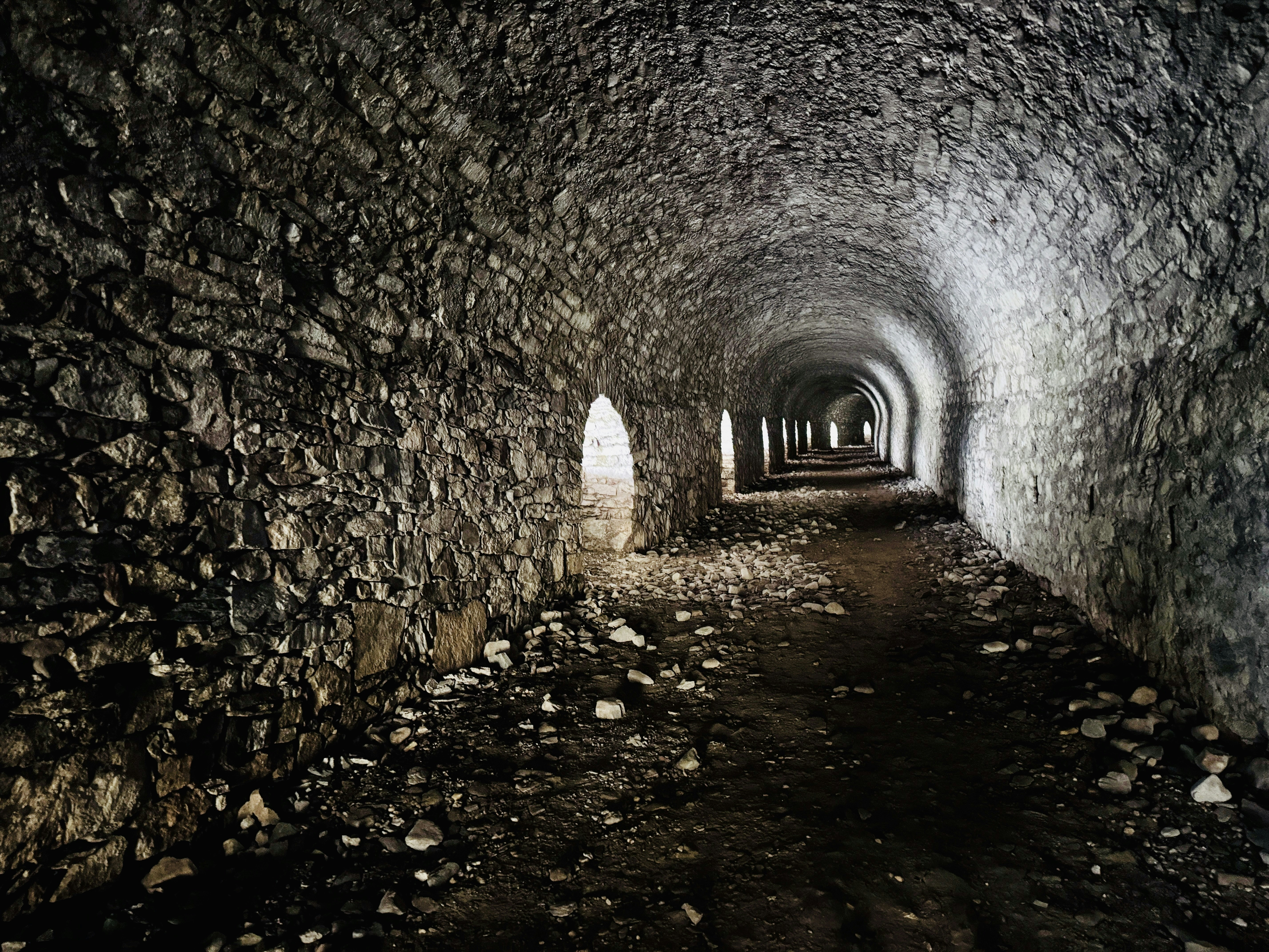 A long stone tunnel with arched openings letting in light from the side