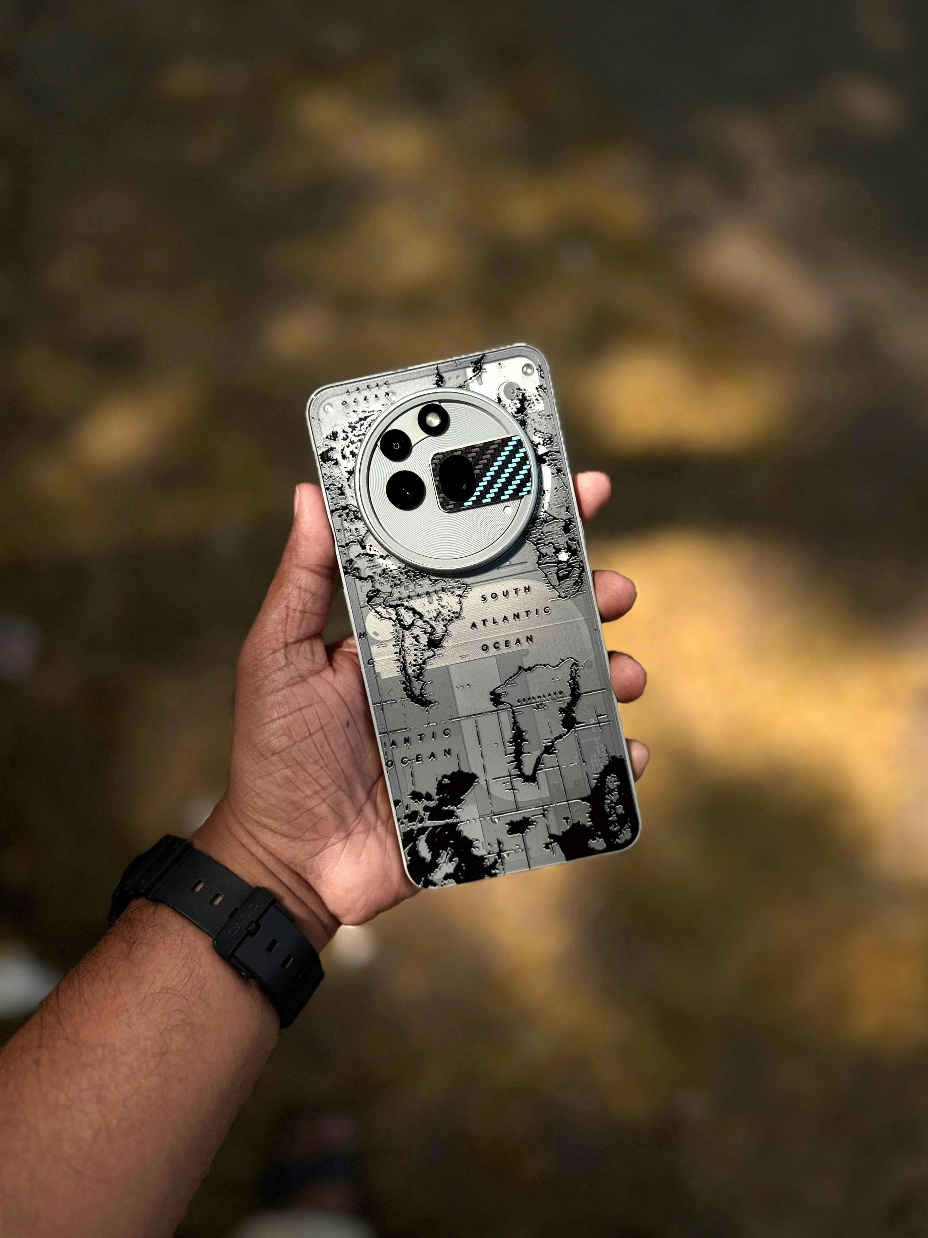 A person holding a smartphone with a world map design on the back