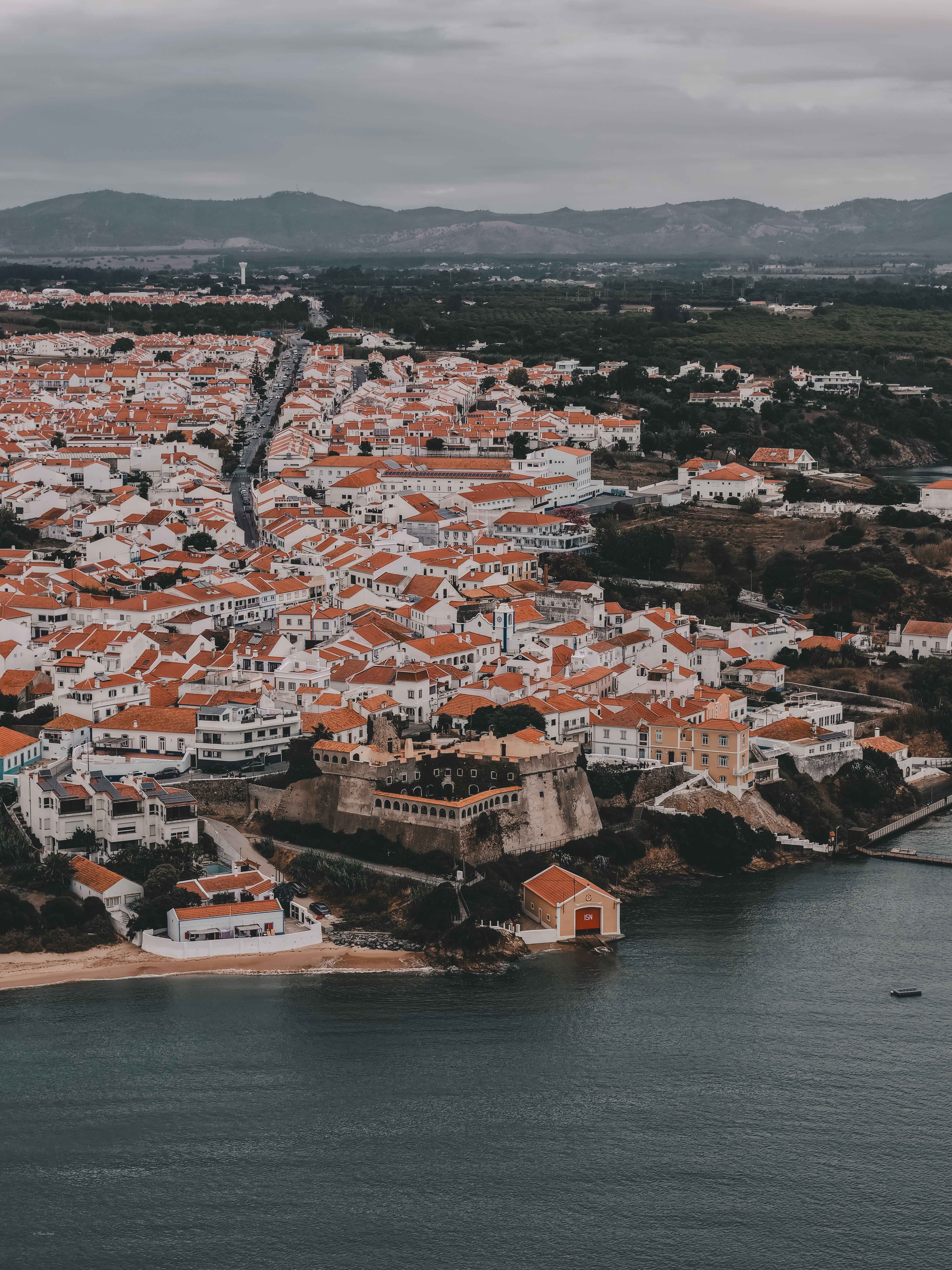 Aerial view of Sines with white buildings and orange roofs along the coast