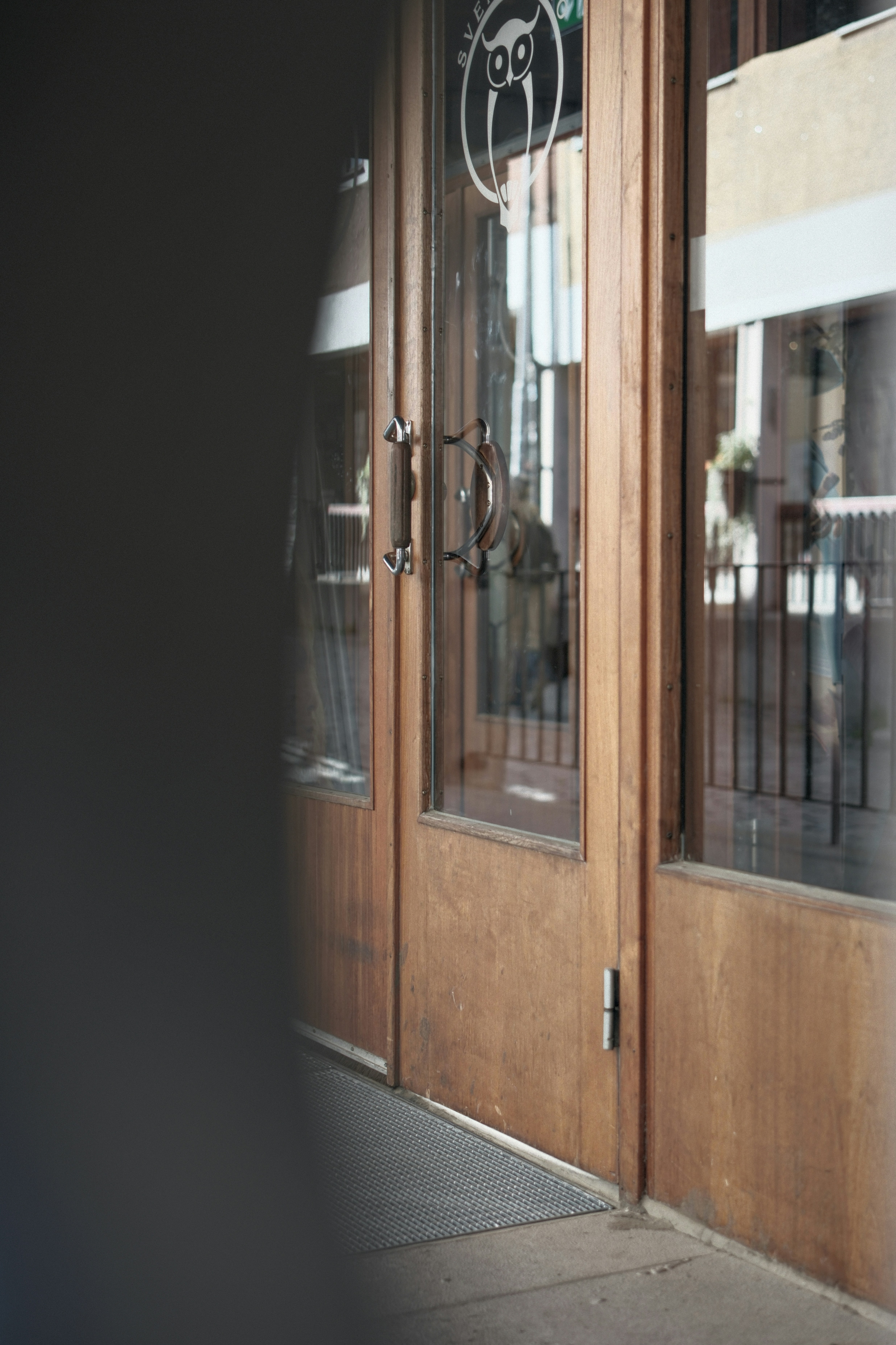 A wooden door with glass panels and an owl logo in a doorway