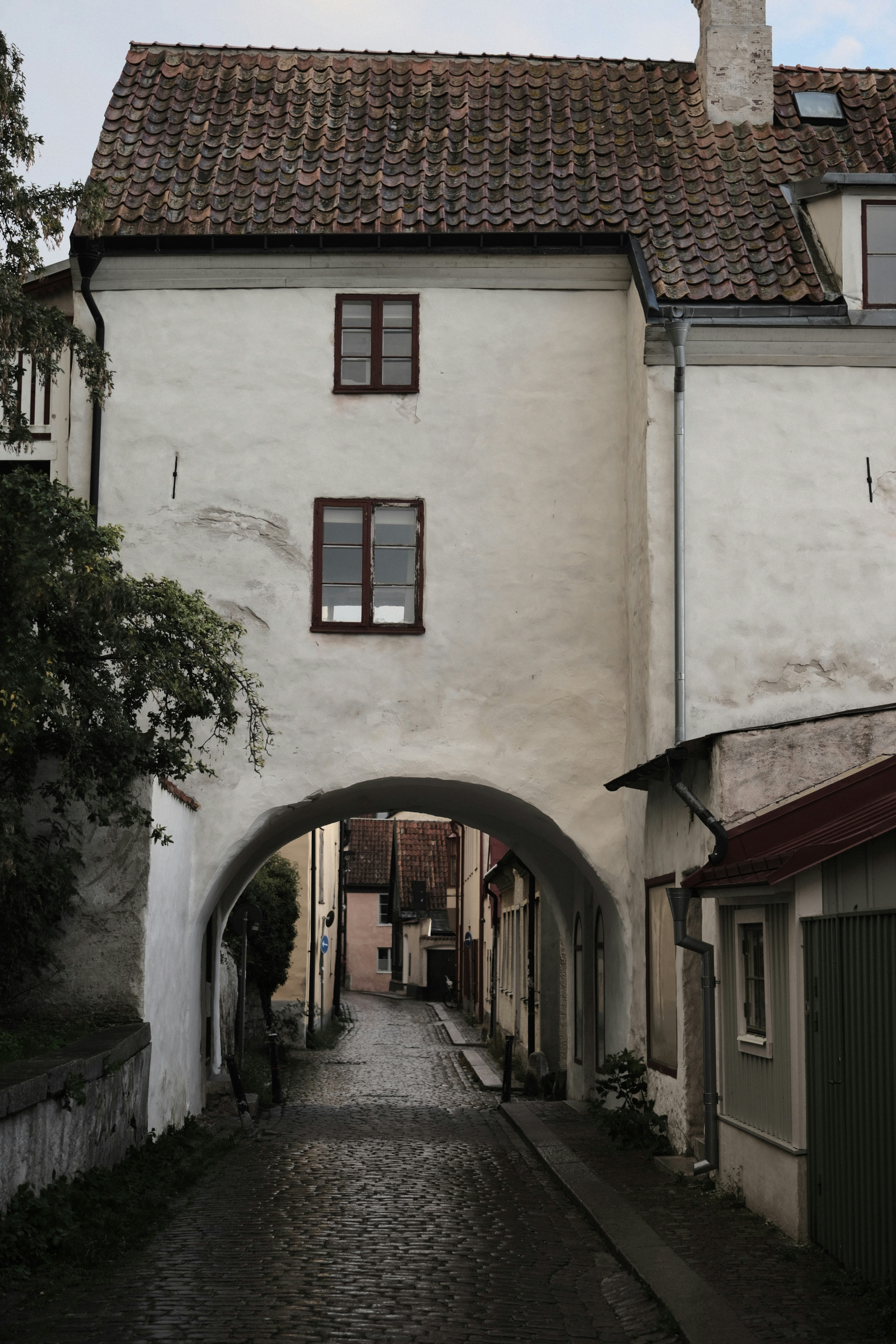 A cobblestone street passing under a white stone archway in a historic town