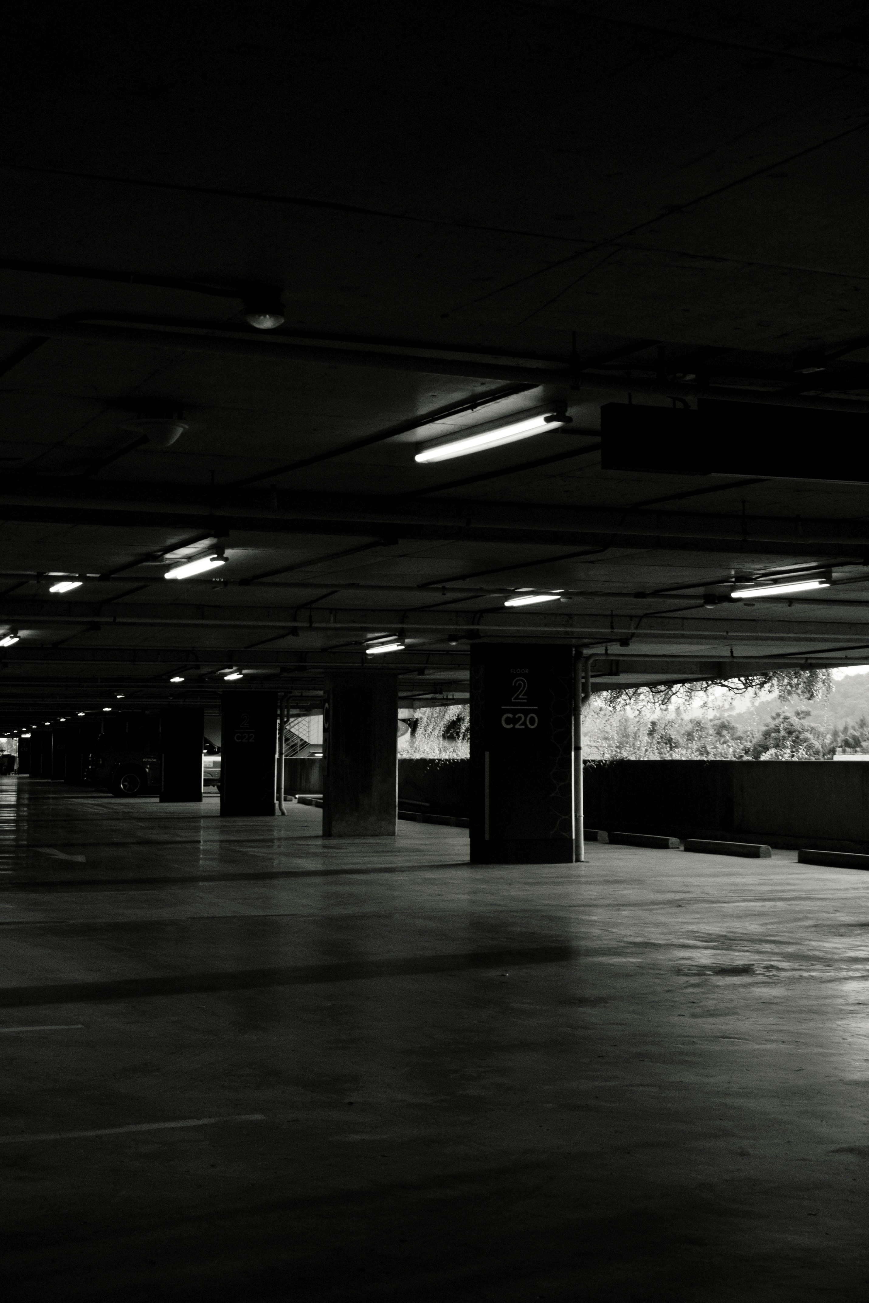 An empty parking garage with concrete pillars and overhead fluorescent lights