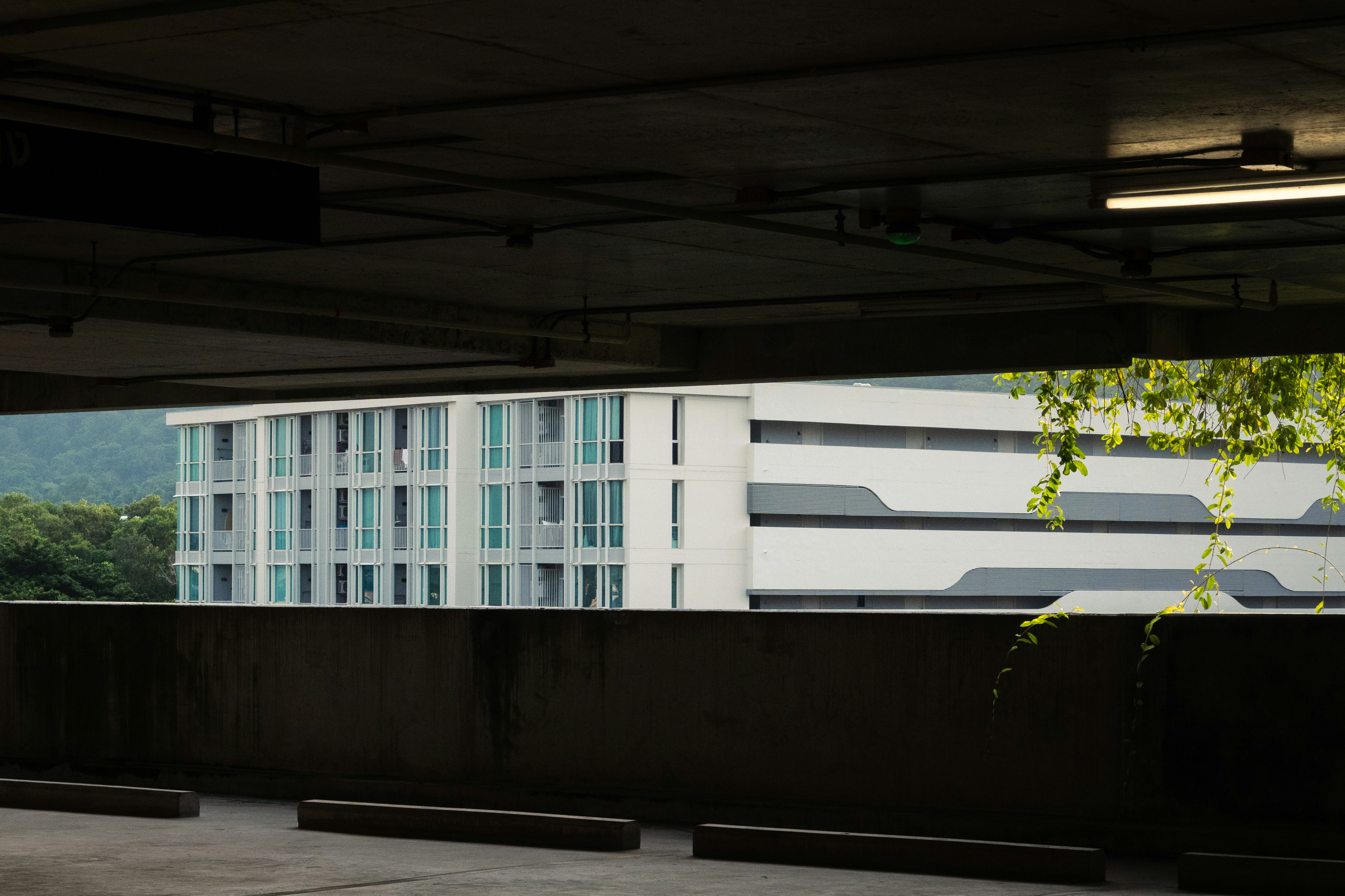 A white apartment building viewed from a dark concrete parking garage