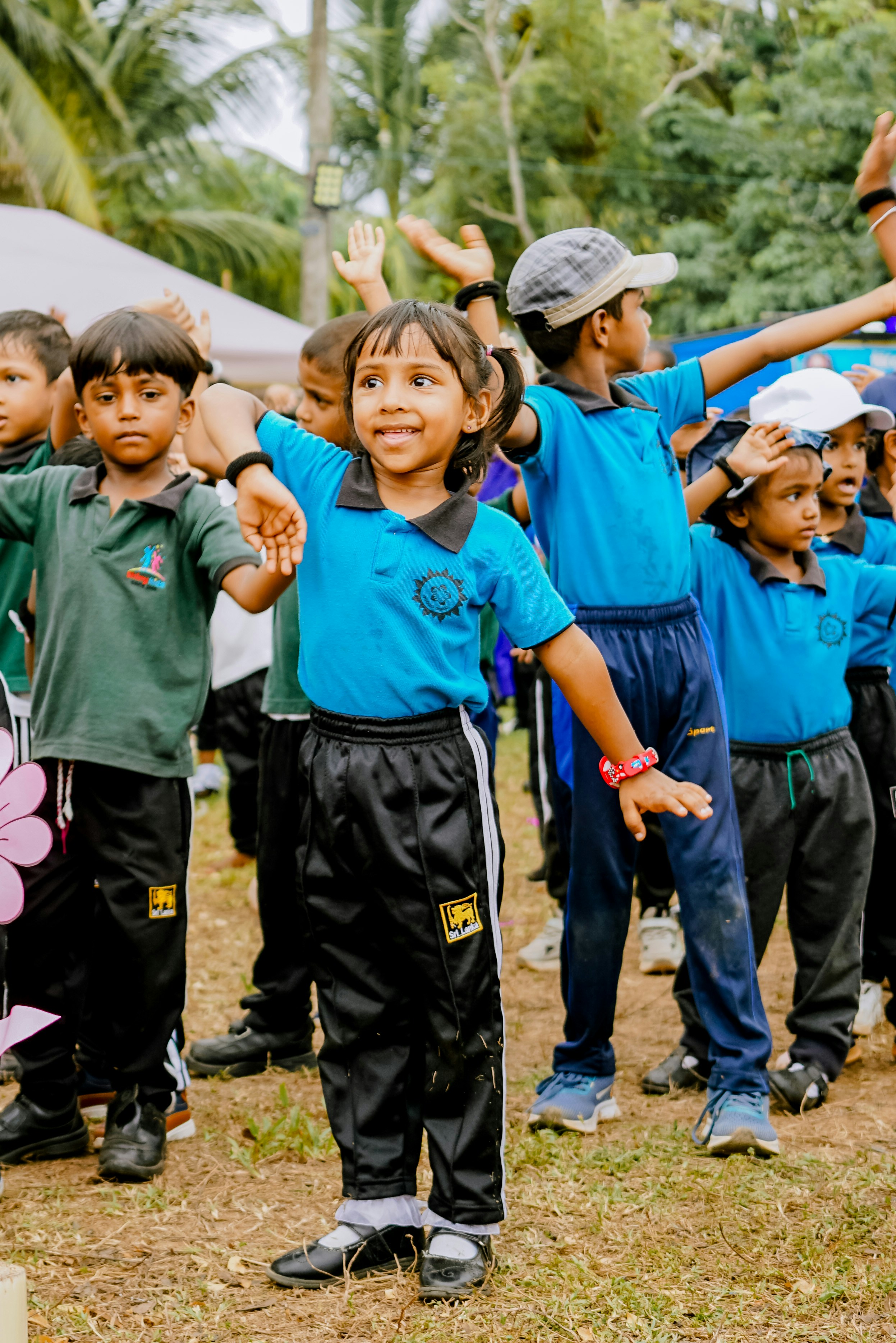 A group of children in school uniforms dancing on a grassy field
