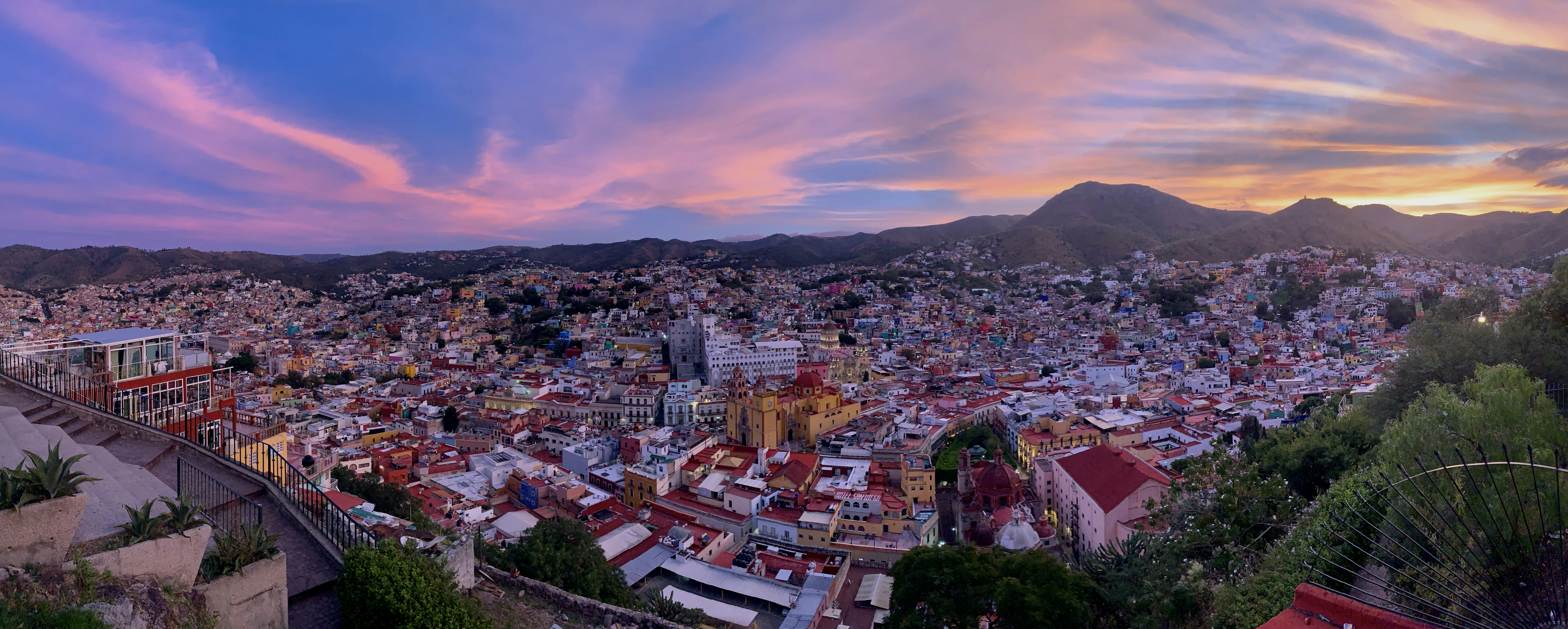 Panoramic view of the colorful city of Guanajuato under a vibrant pink sky