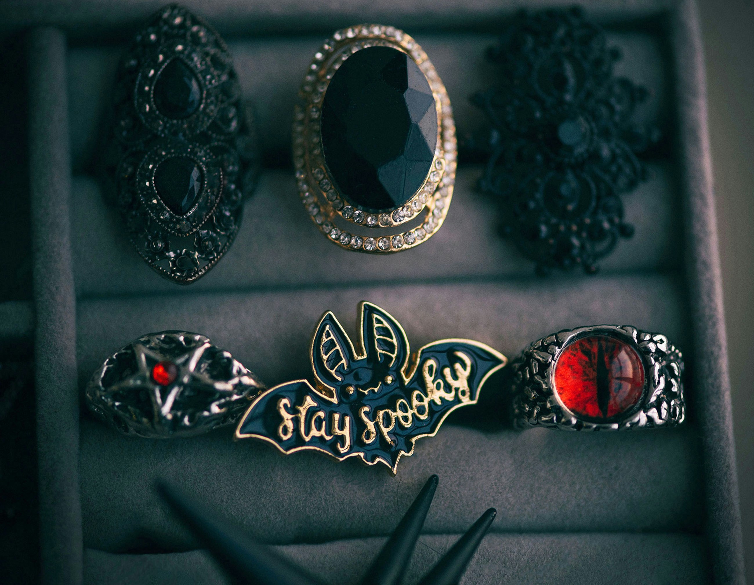 Gothic rings and a bat pin reading "stay spooky" in a jewellery box