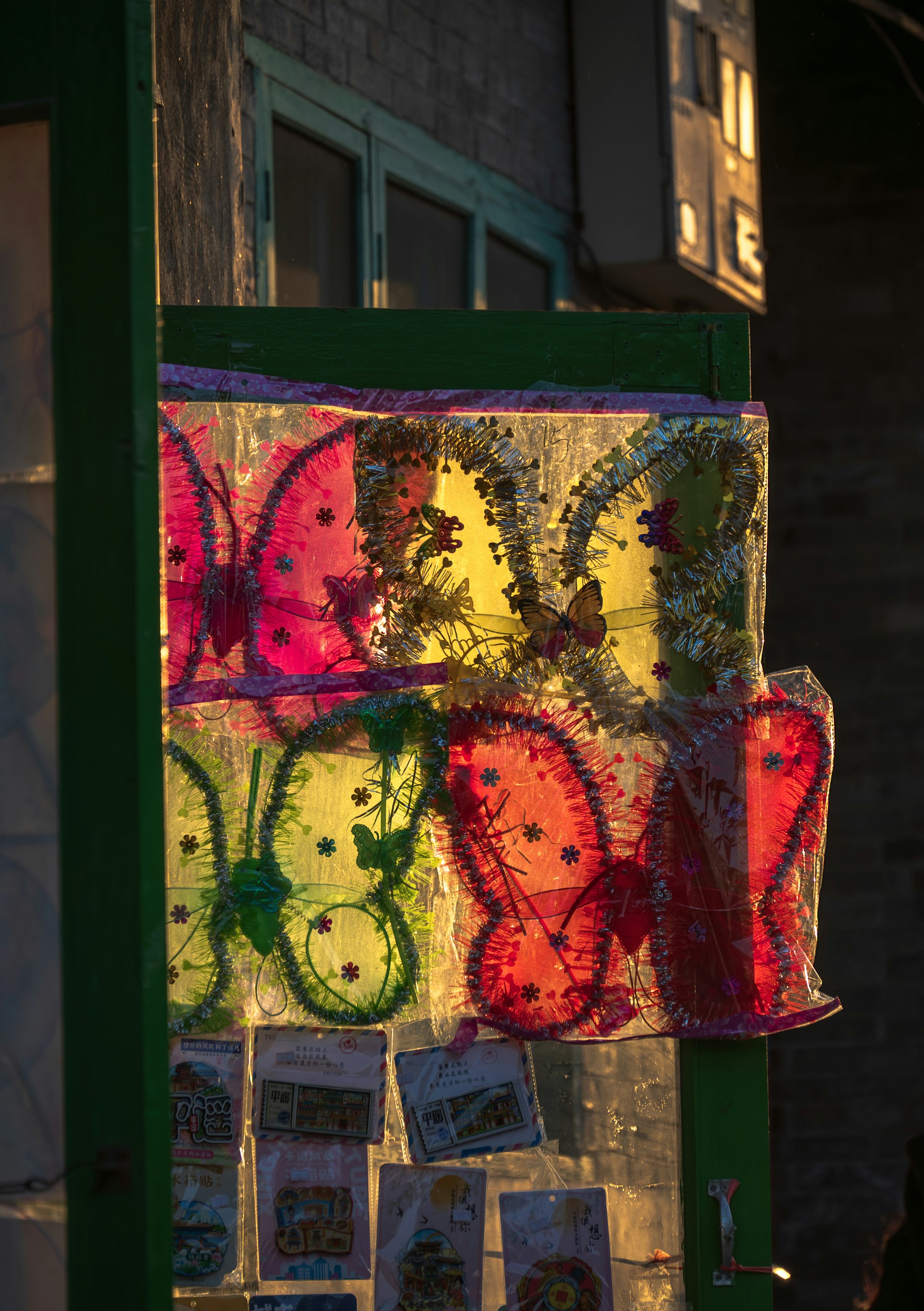 Colorful butterfly-shaped decorations in plastic packaging hanging on a green frame