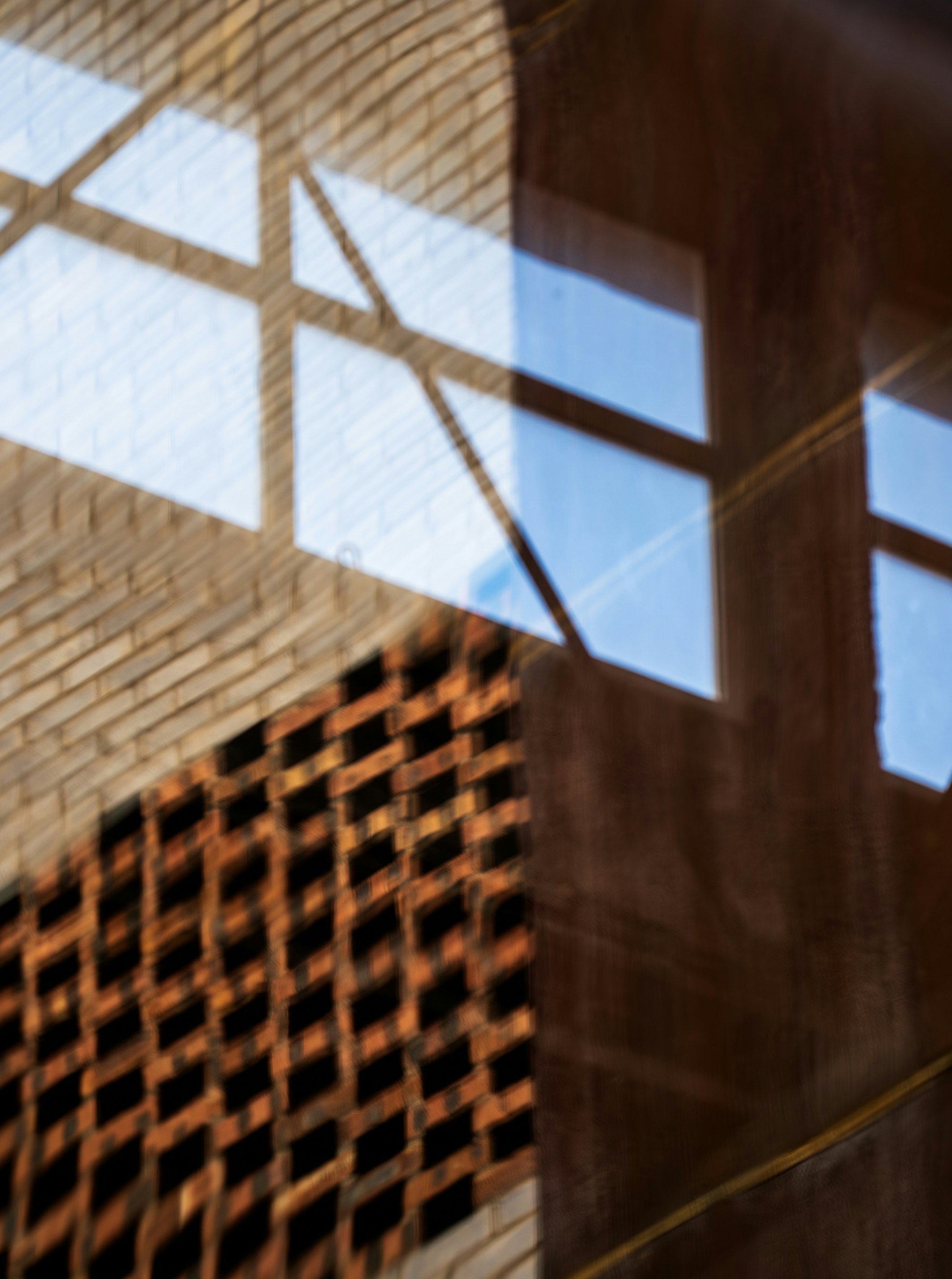 Reflection of a window and brick wall on a dark glass surface
