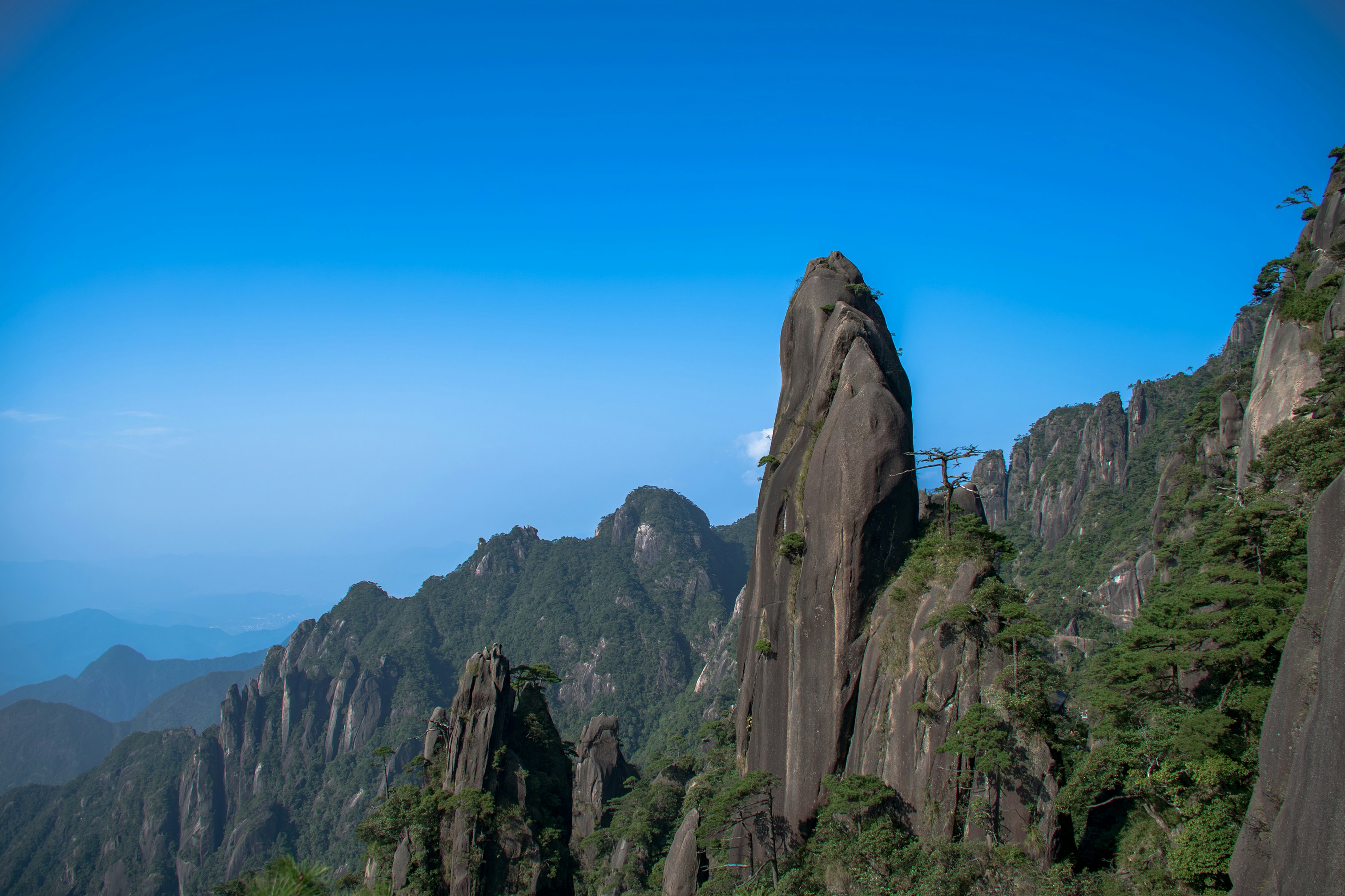 Tall granite rock formations with pine trees under a clear blue sky