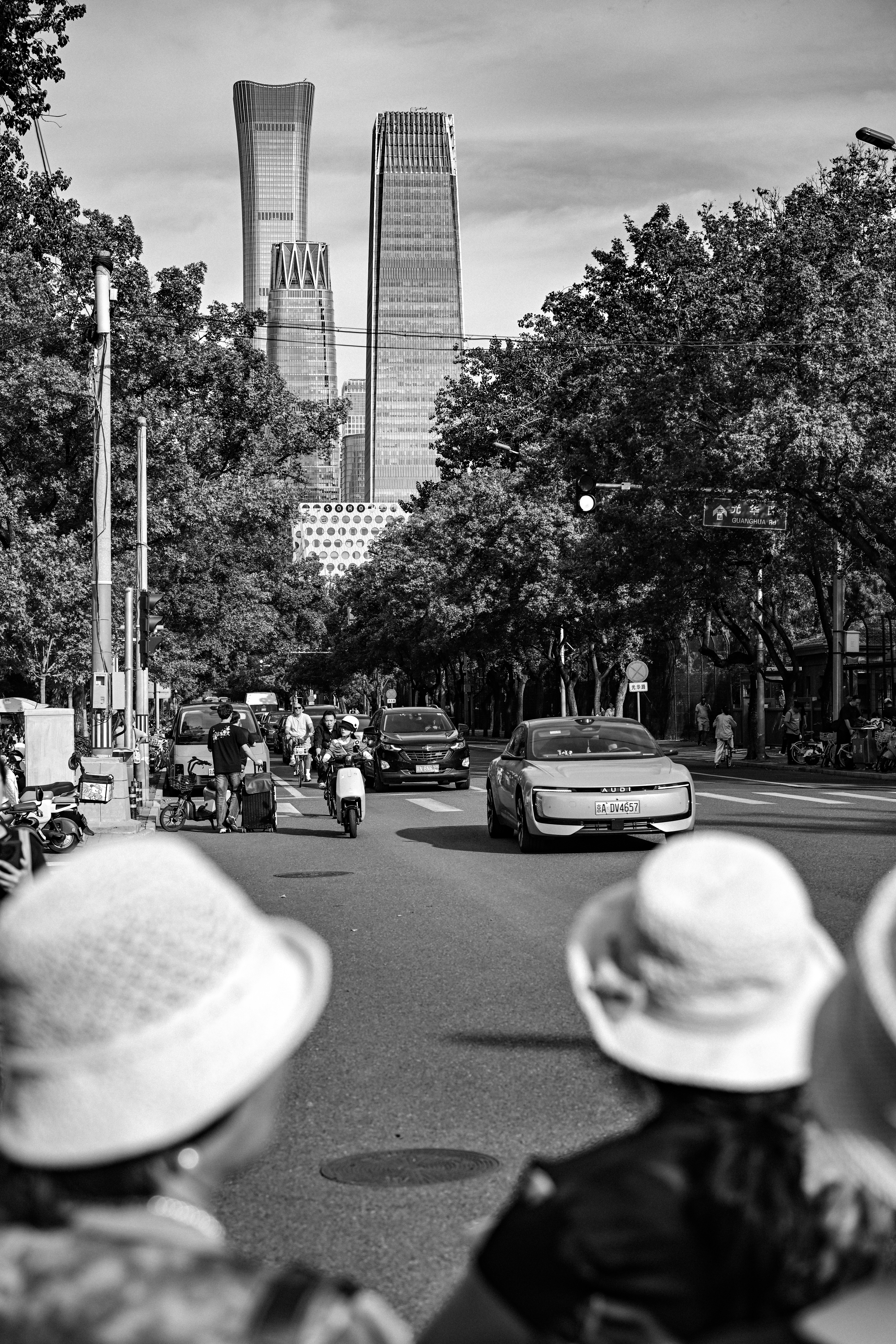 Traffic on a tree-lined street in Beijing with modern skyscrapers in the background
