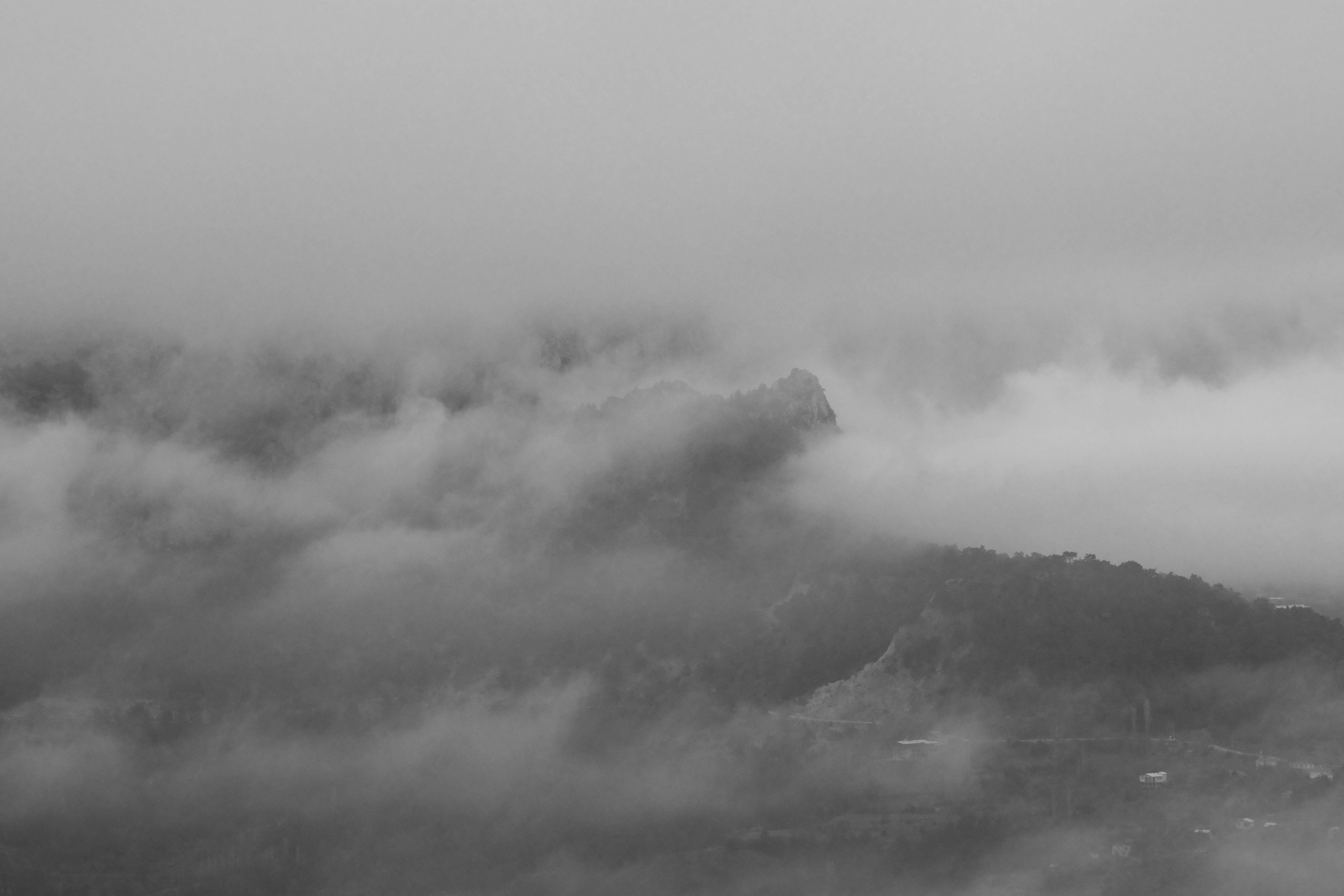 A rocky mountain summit emerging through thick layers of grey mist