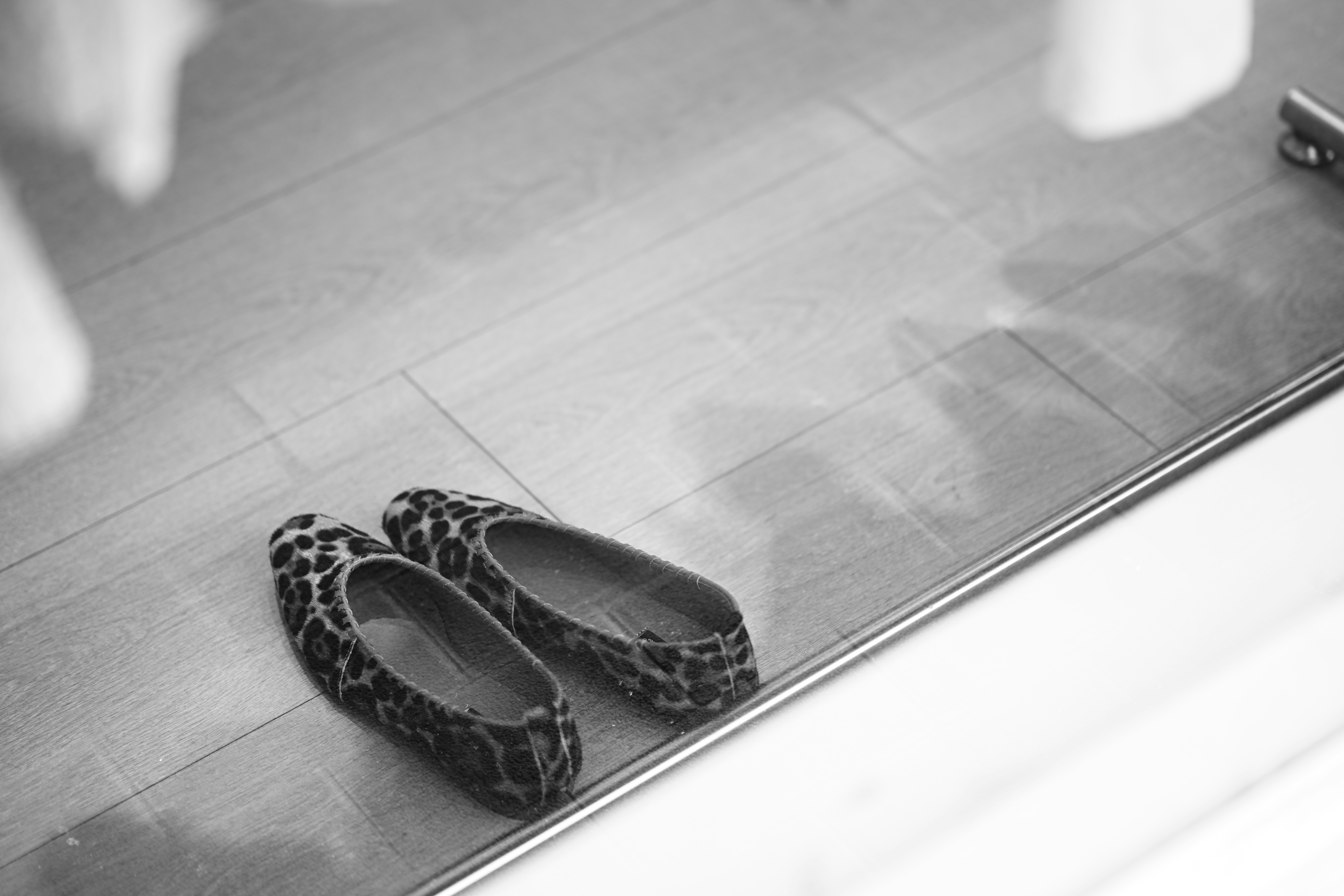 A pair of leopard print ballet flats on a wooden floor