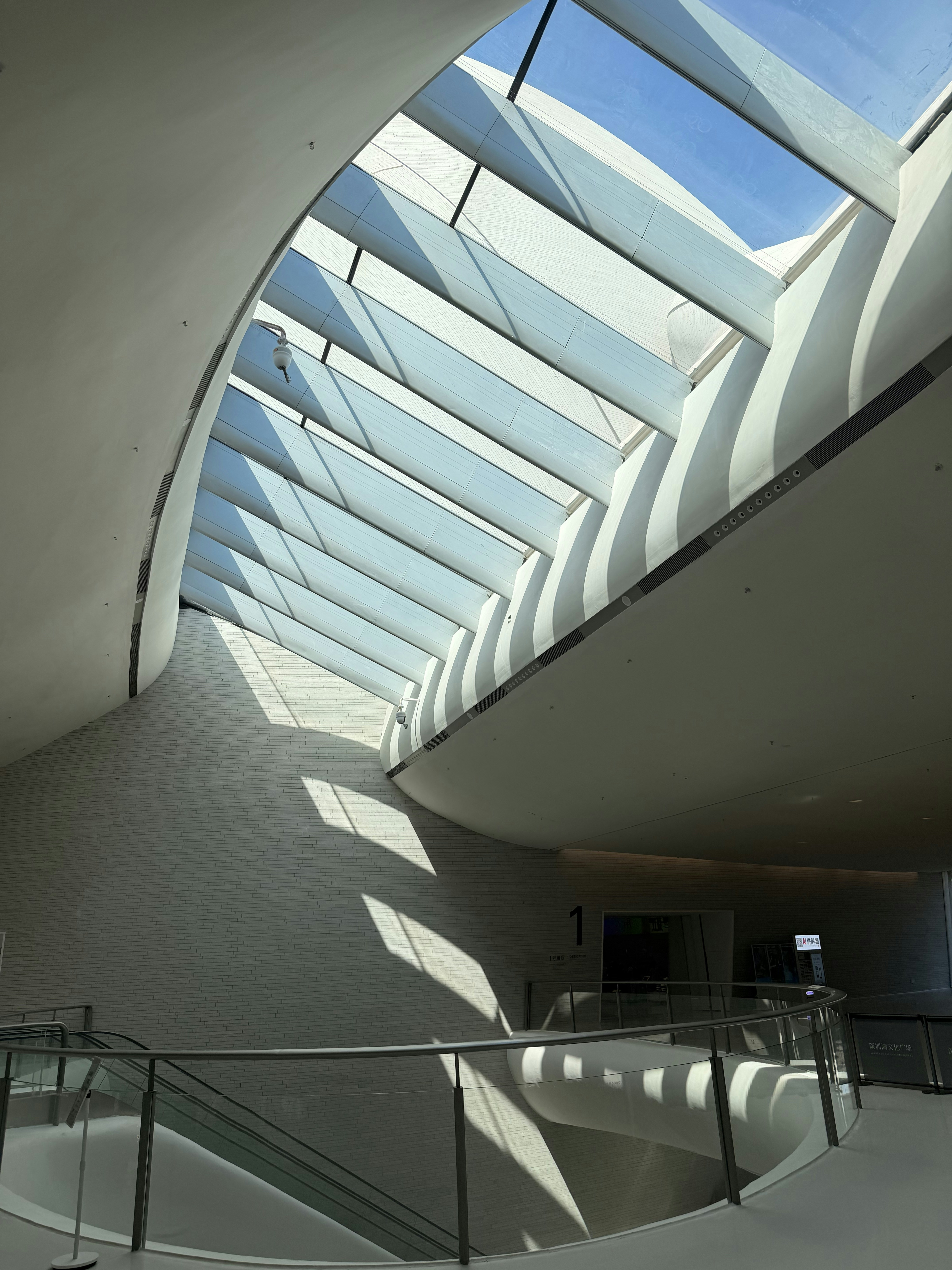 A modern interior with a curved ceiling and a large glass skylight