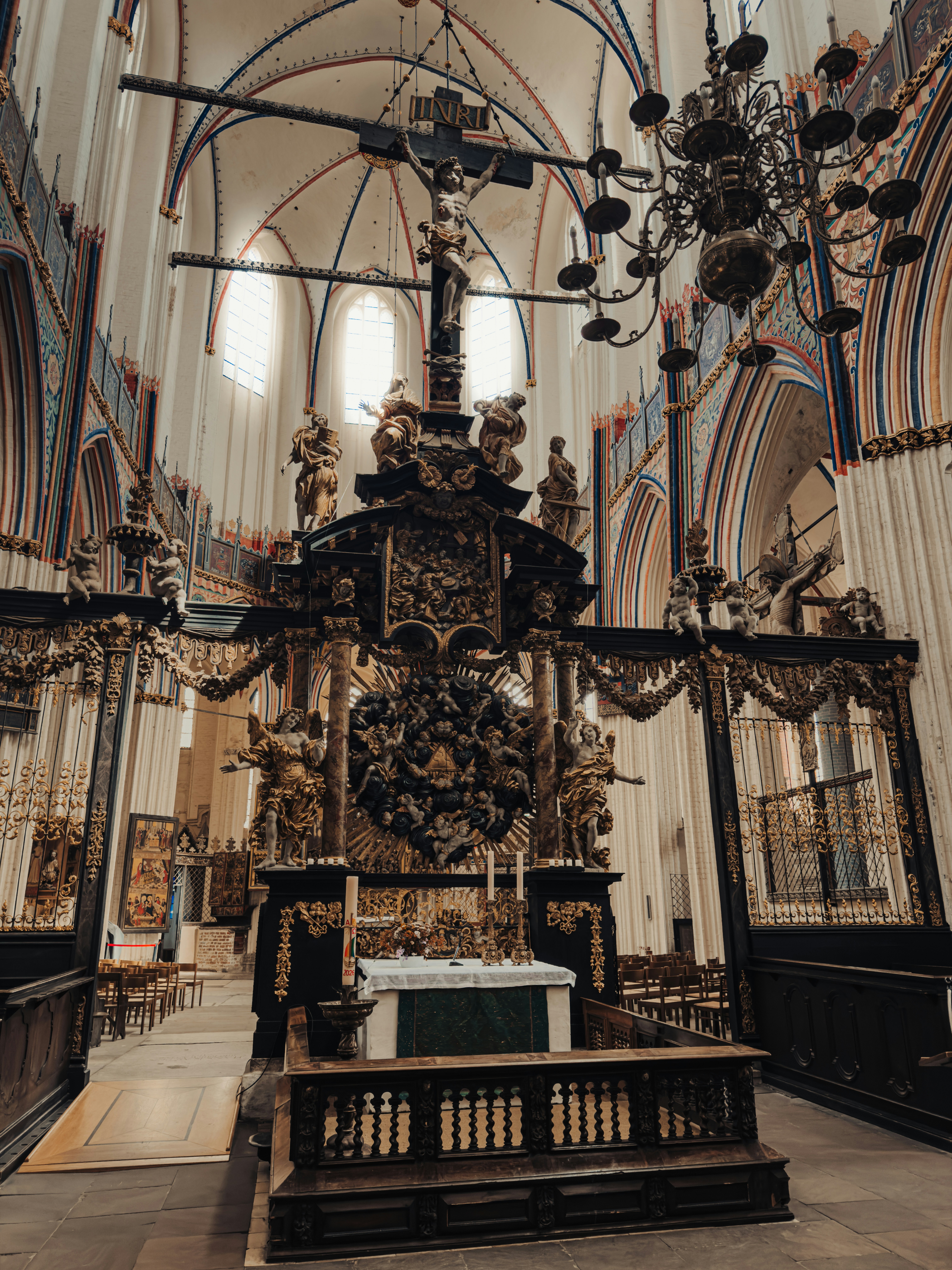 Ornate gothic altar with a crucifix and statues inside a vaulted stone church
