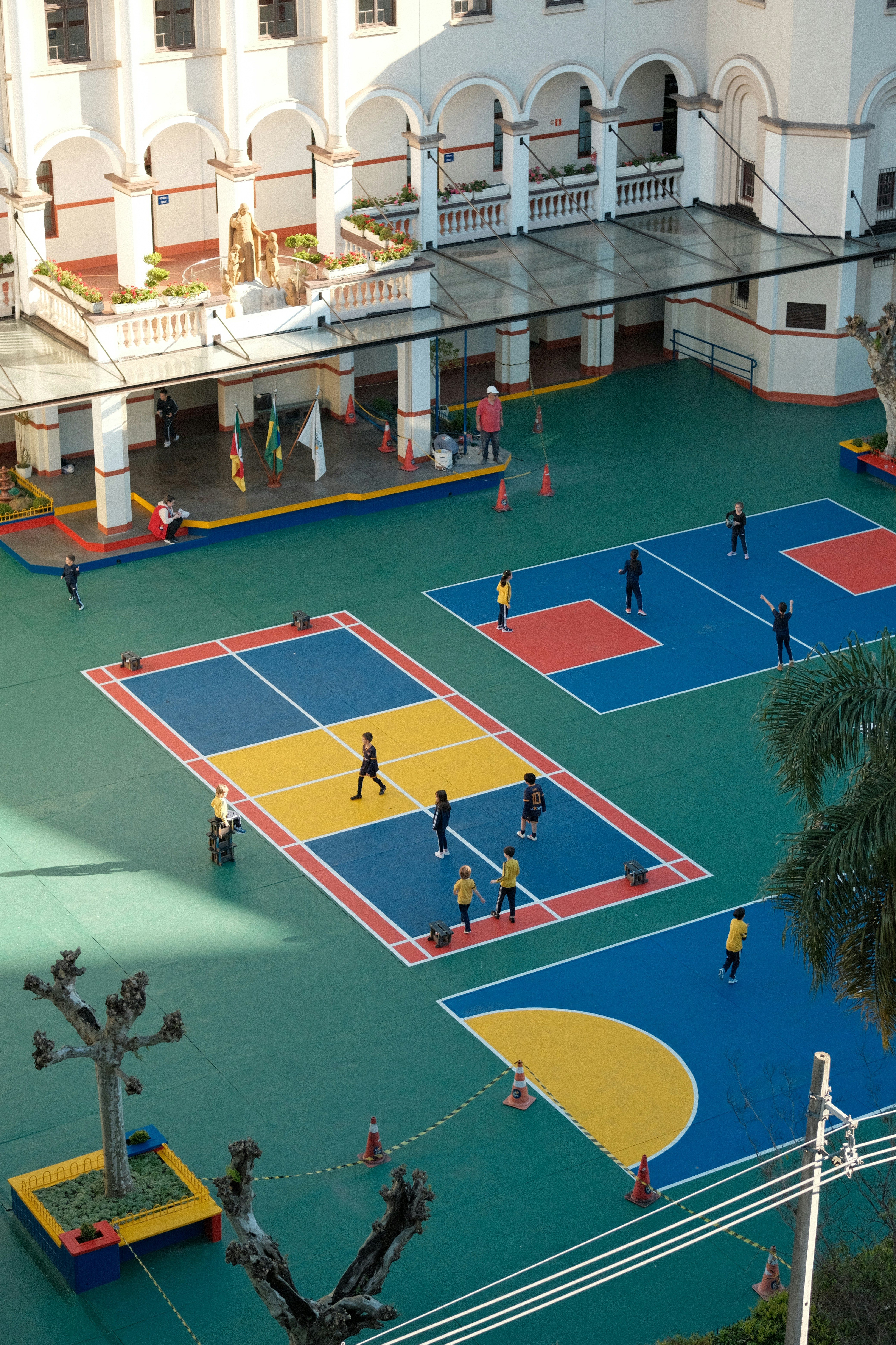 Children playing on a colorful outdoor sports court in a school courtyard