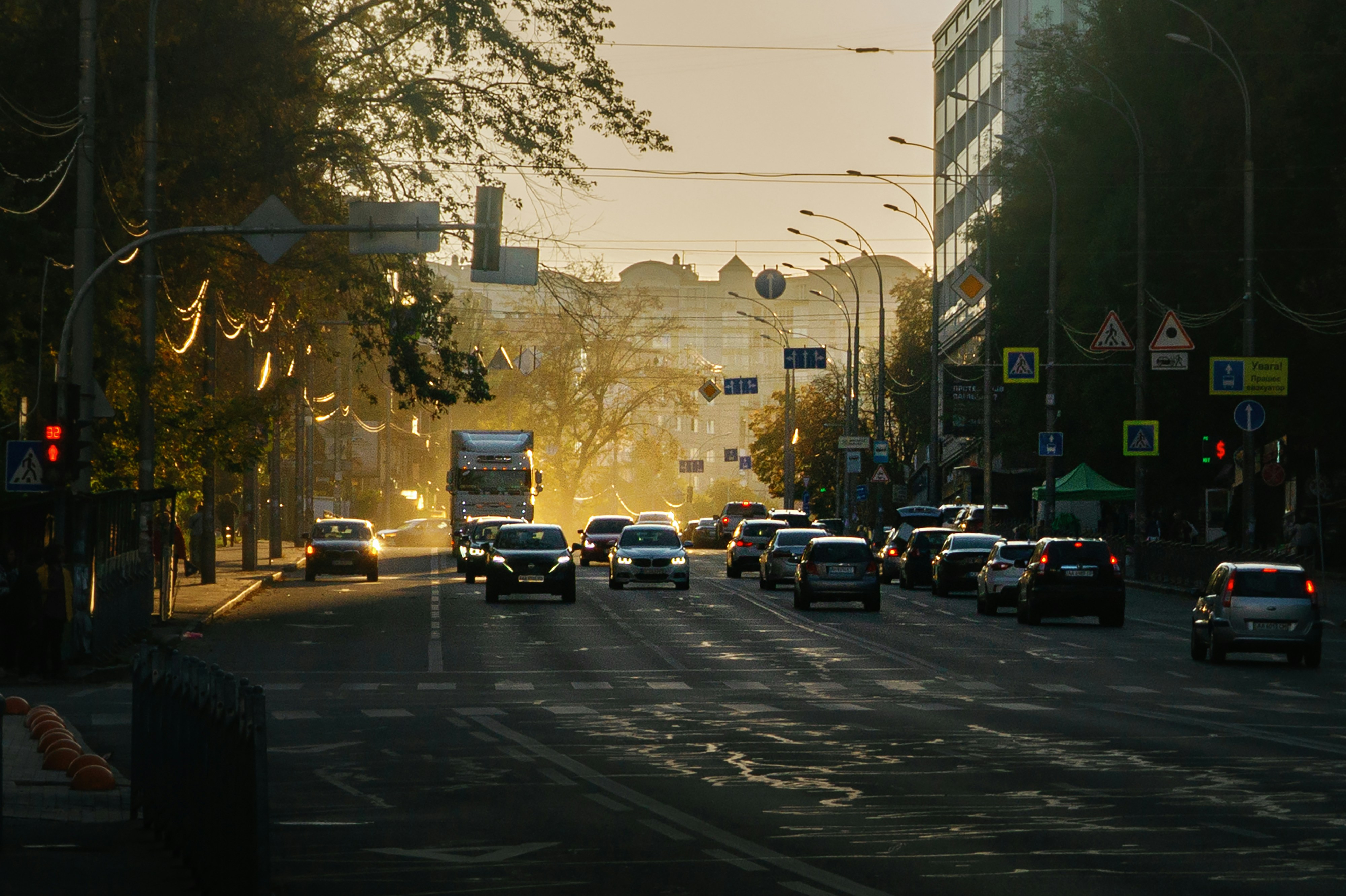 Cars driving on a city street during golden hour with long shadows and hazy light