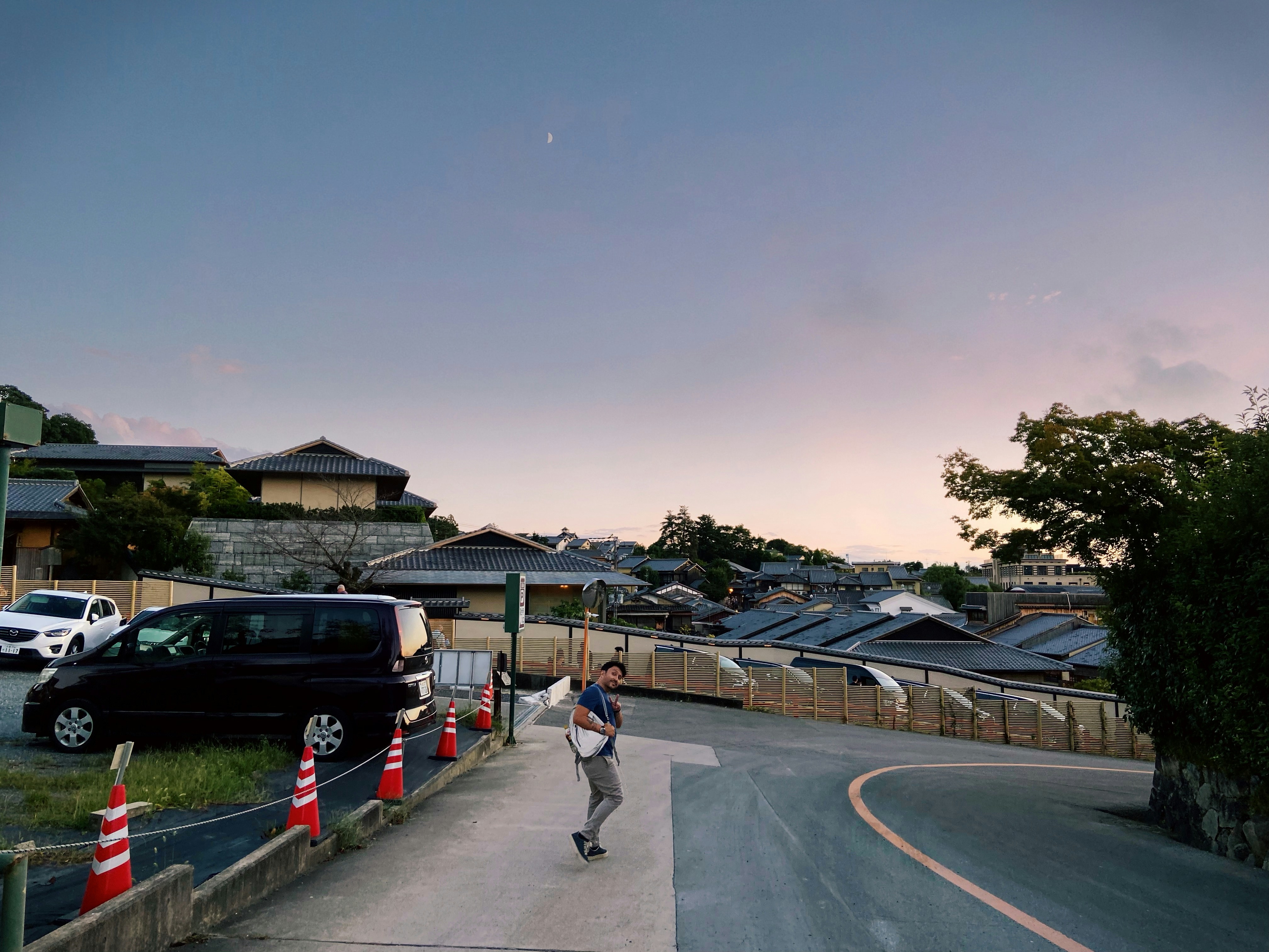 A person with a backpack walking on a road near traditional Japanese houses