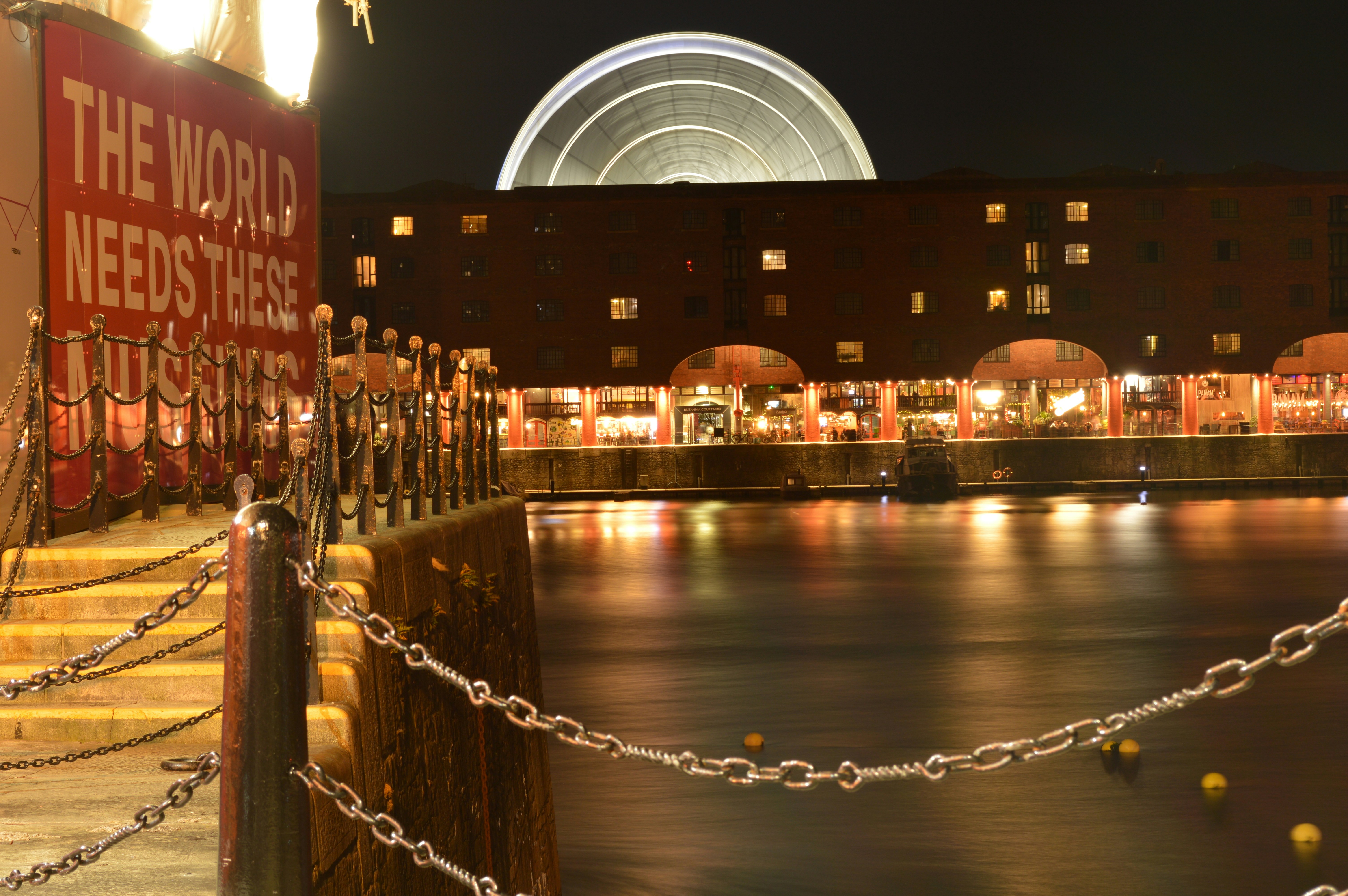 A long exposure of a ferris wheel behind a brick building at night
