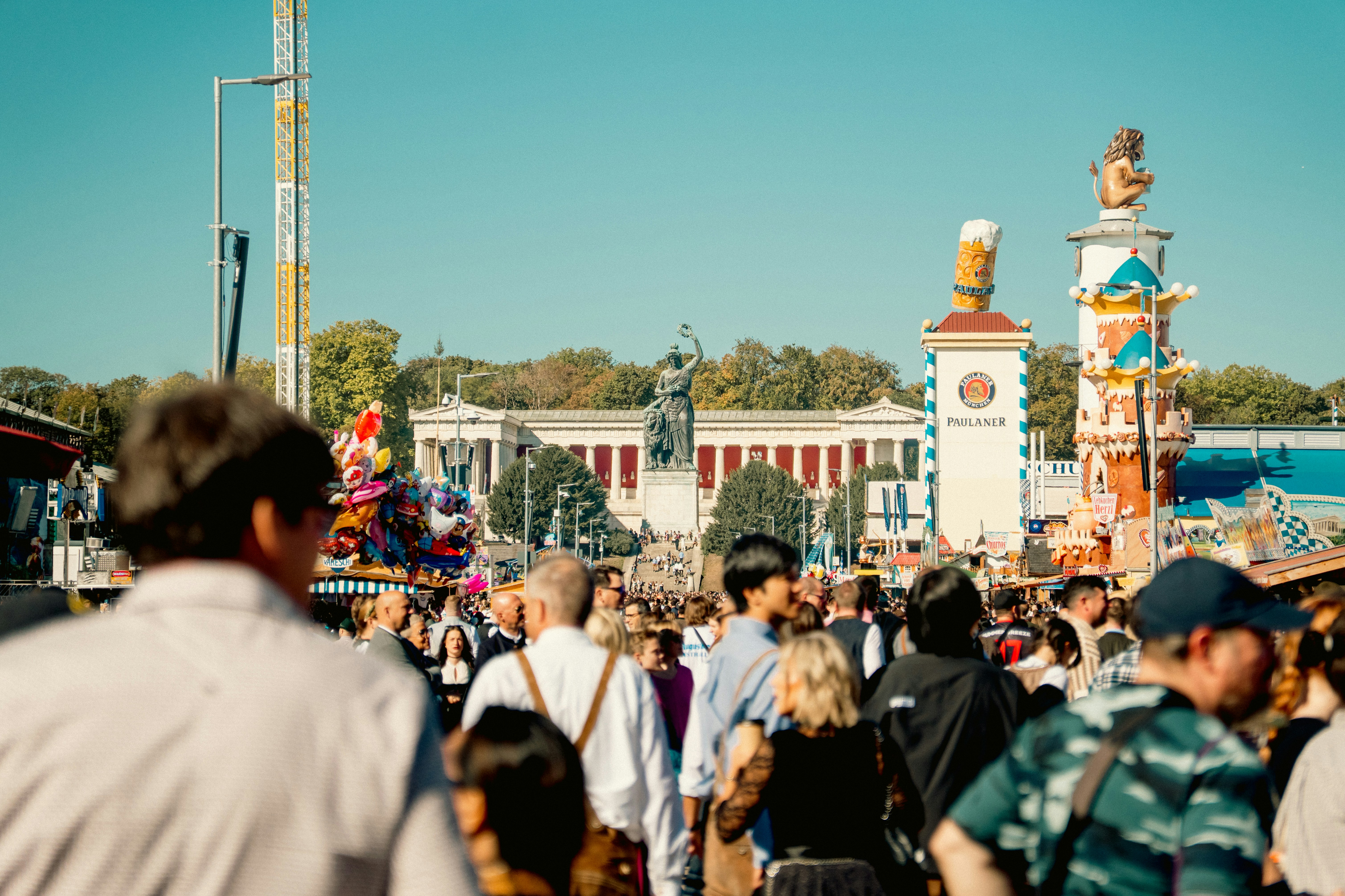 A crowd of people at the Oktoberfest festival in Munich with the Bavaria statue
