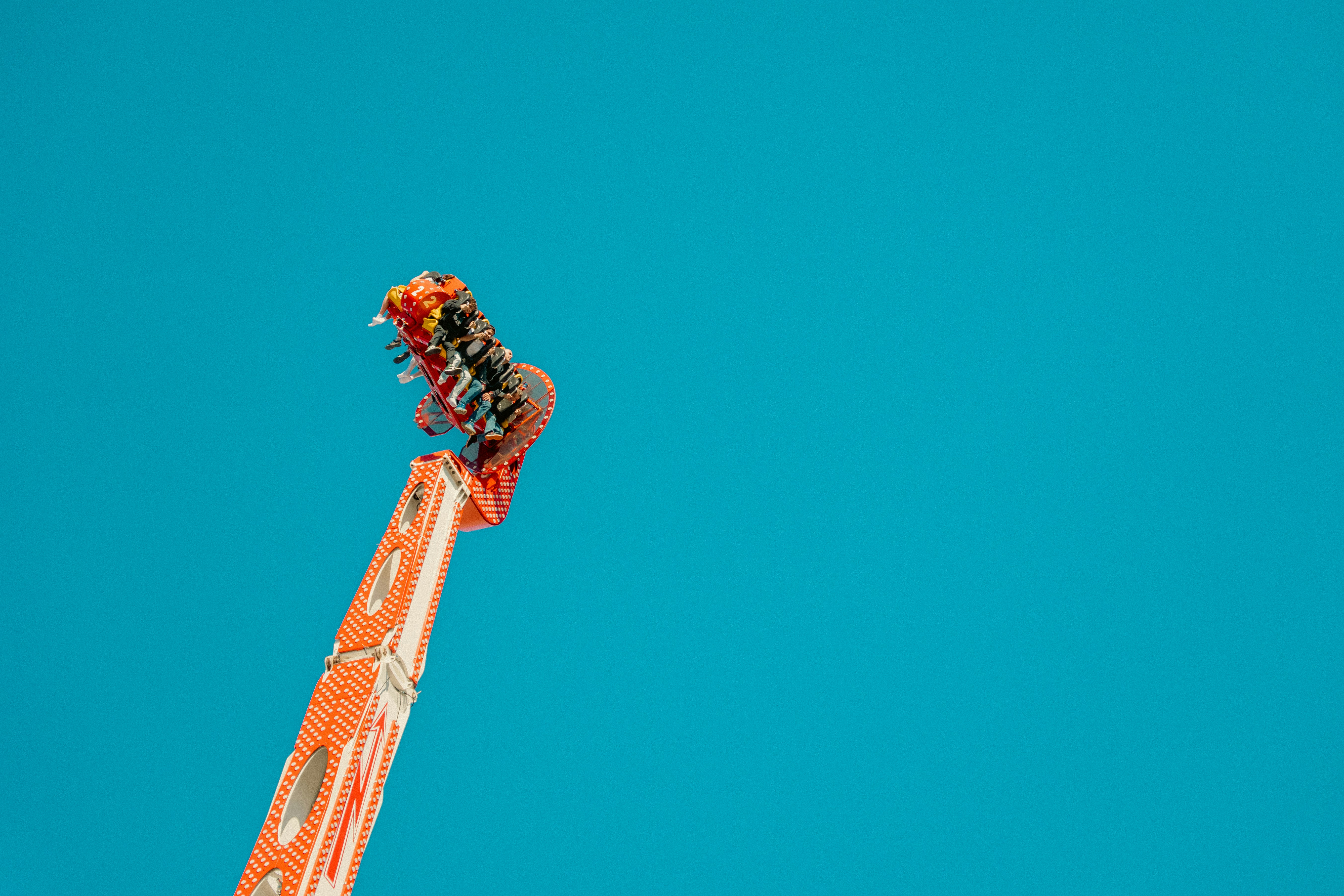 People riding a spinning amusement park ride against a clear blue sky