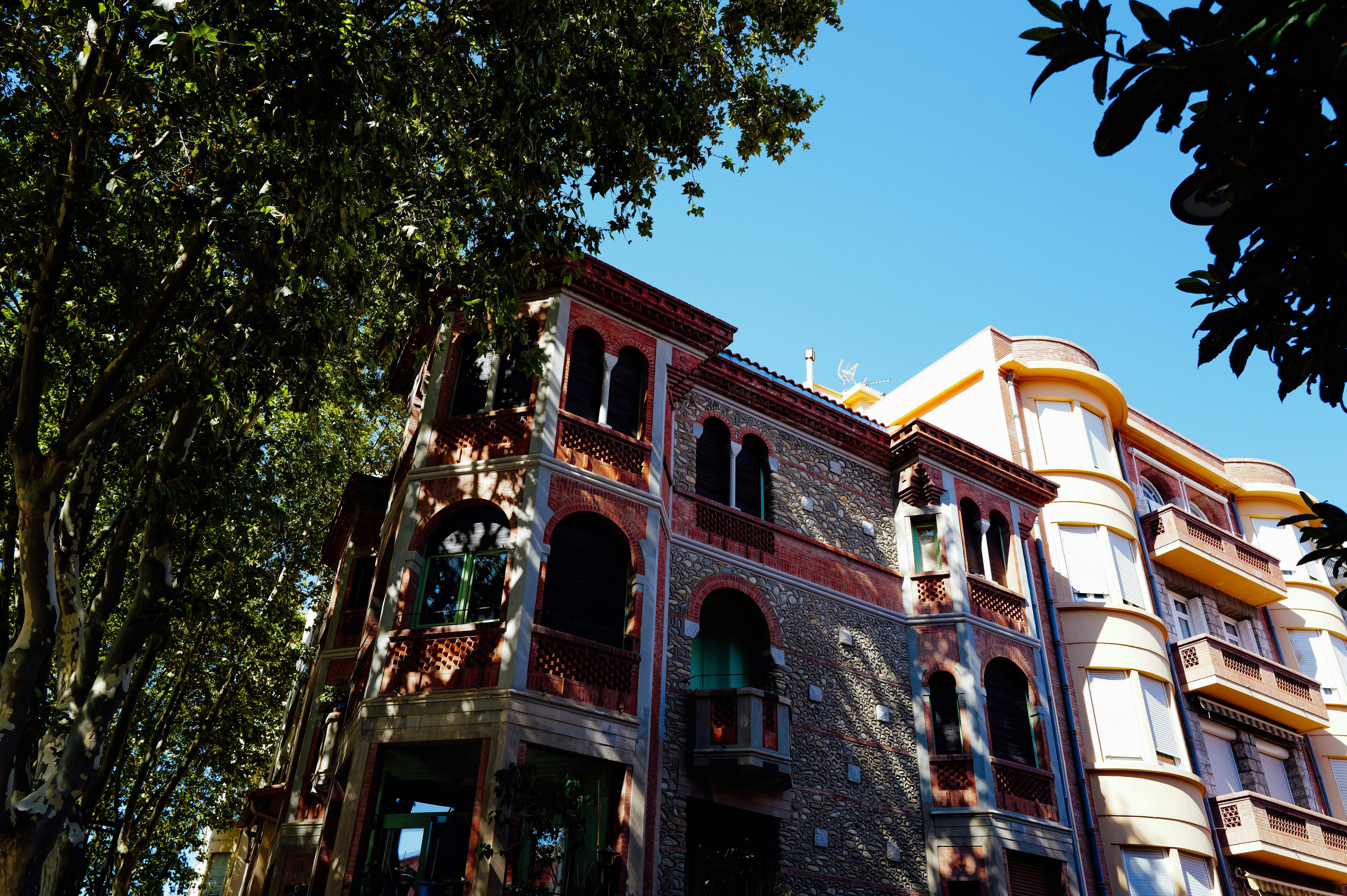 Um edifício histórico de tijolos e pedra com janelas arqueadas sob um céu azul claro