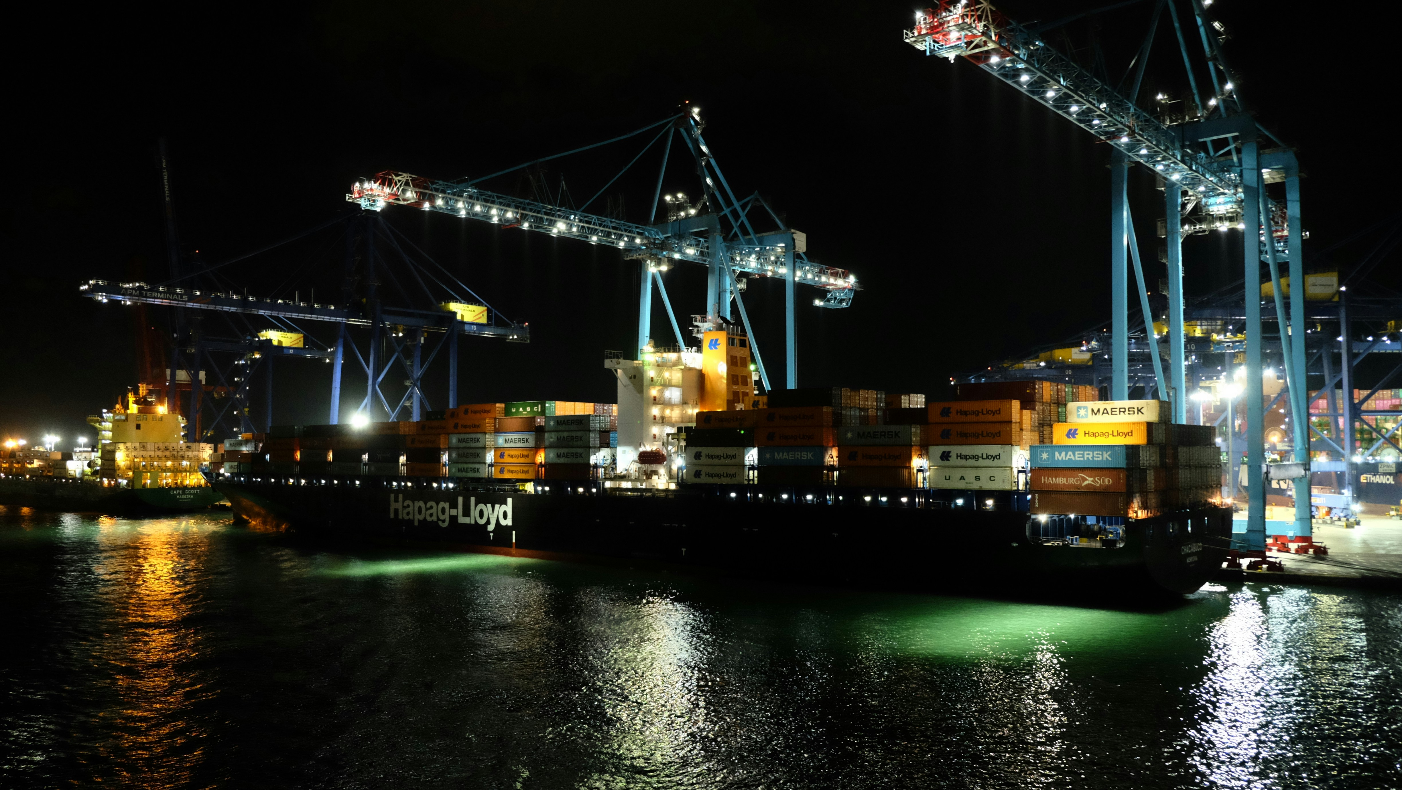 Una nave portacontainer attraccata in un porto di notte sotto grandi gru