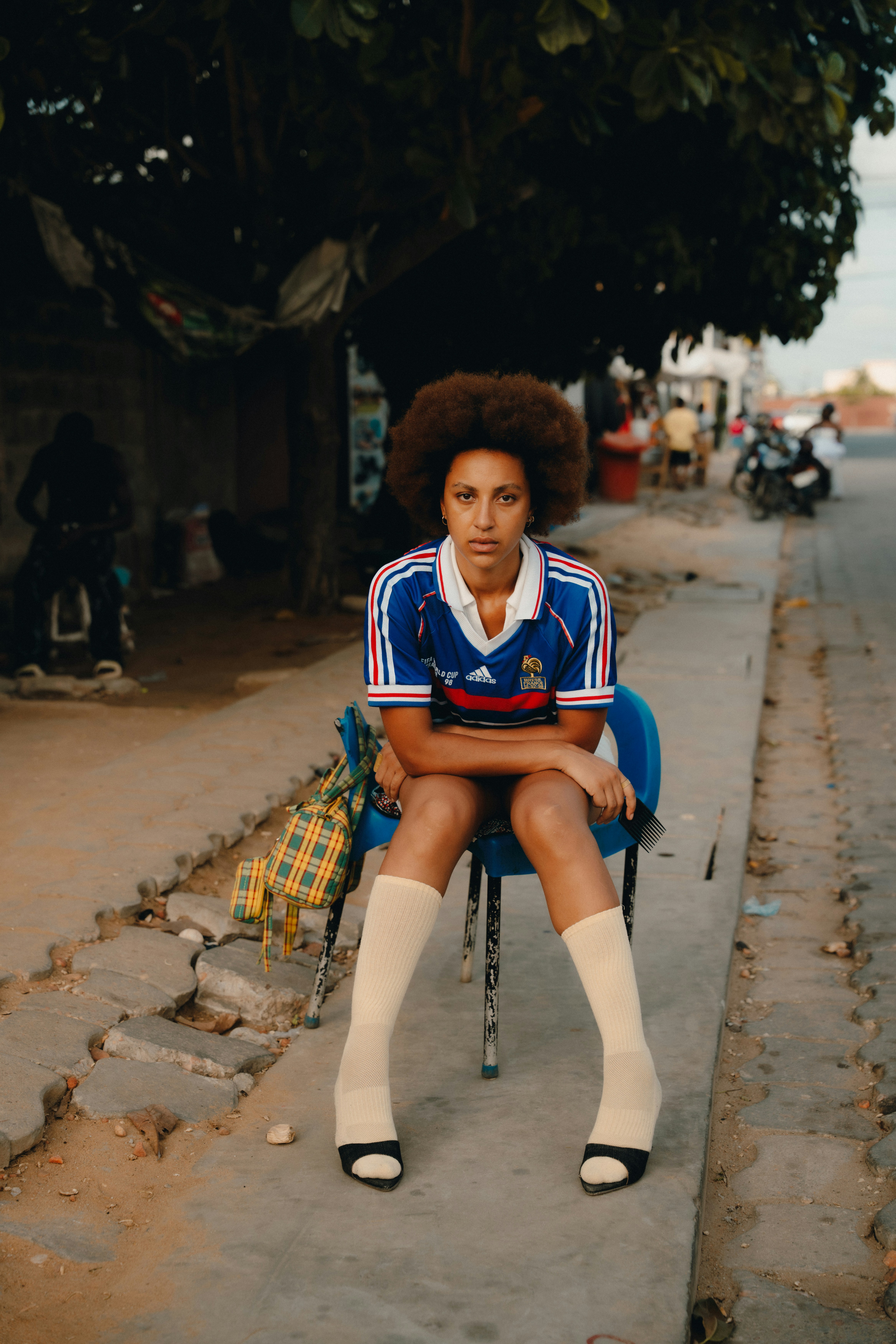 A woman with an afro wearing a blue soccer jersey and knee-high socks