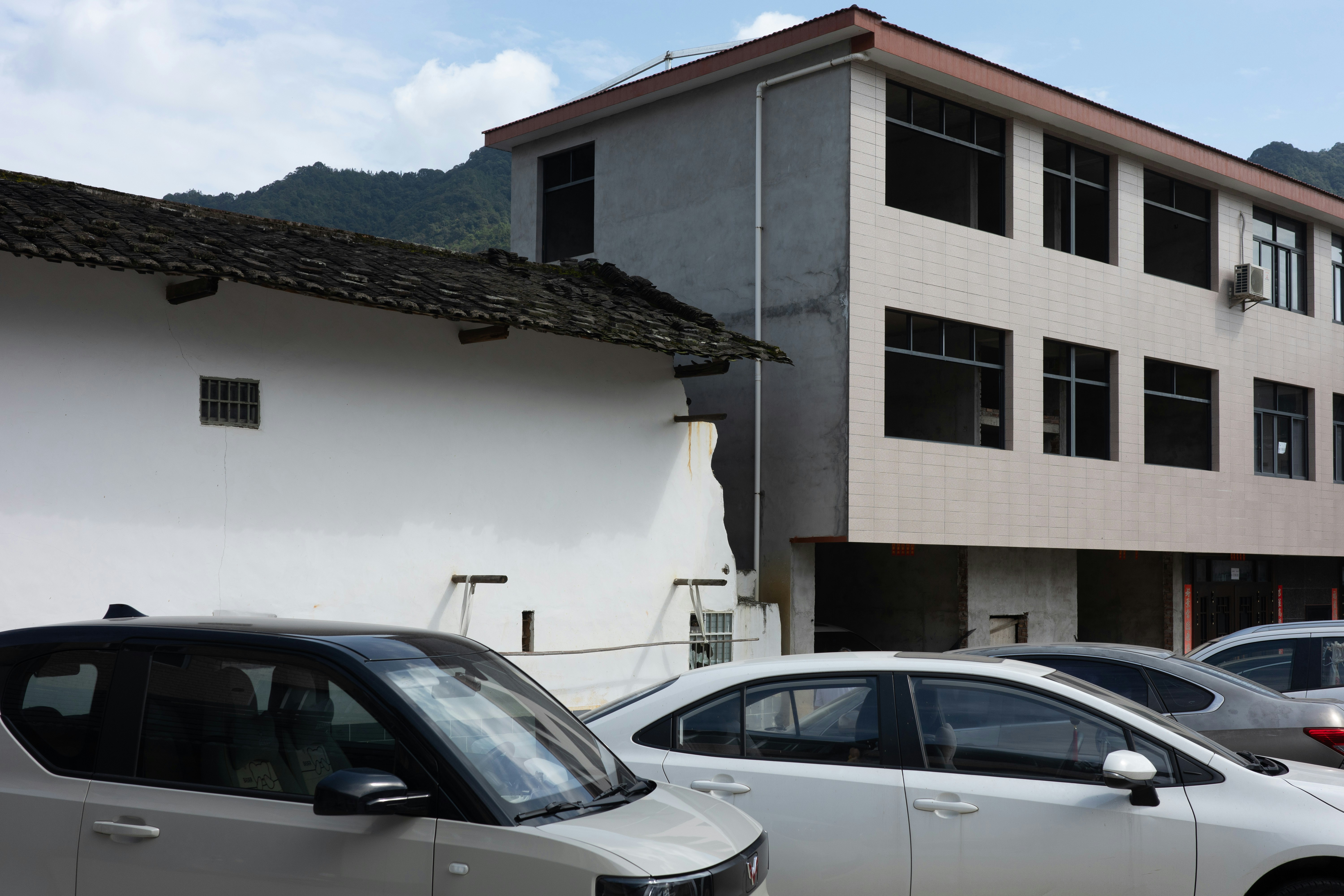 White cars parked in front of a traditional white building and a modern structure