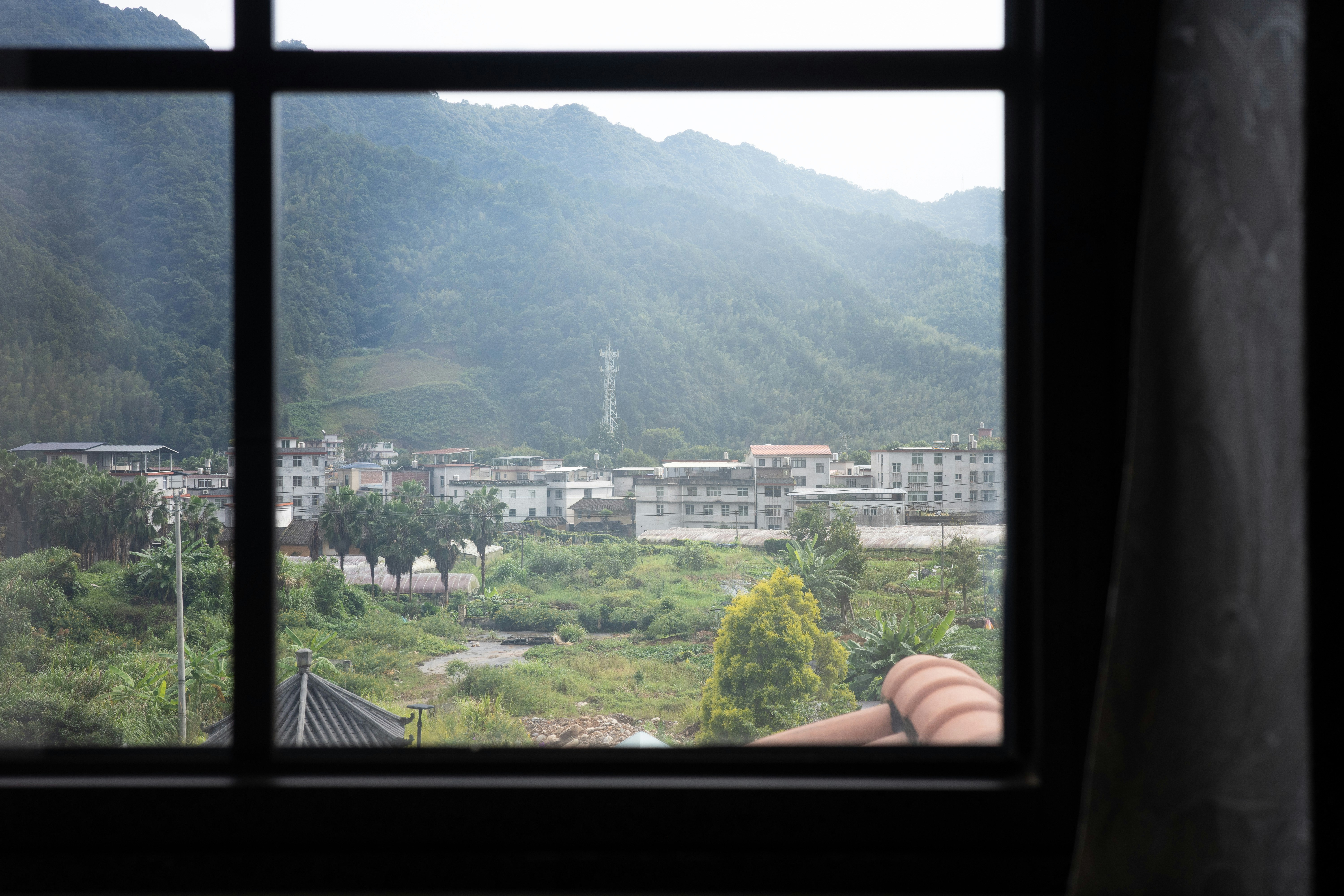 A view through a window of a small town nestled against green mountains