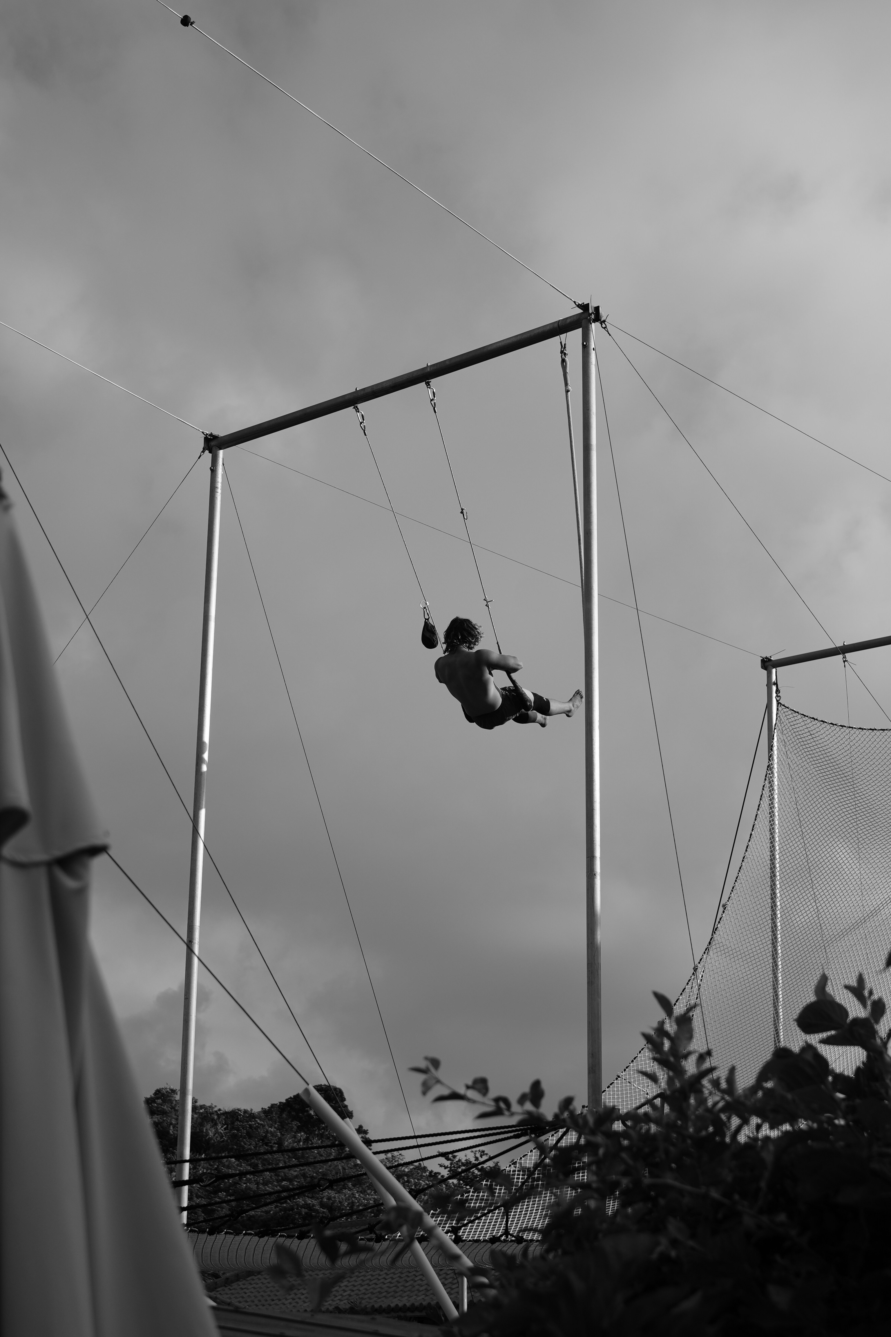 Eine Person, die an einer Trapezstange gegen einen wolkigen Himmel schwingt