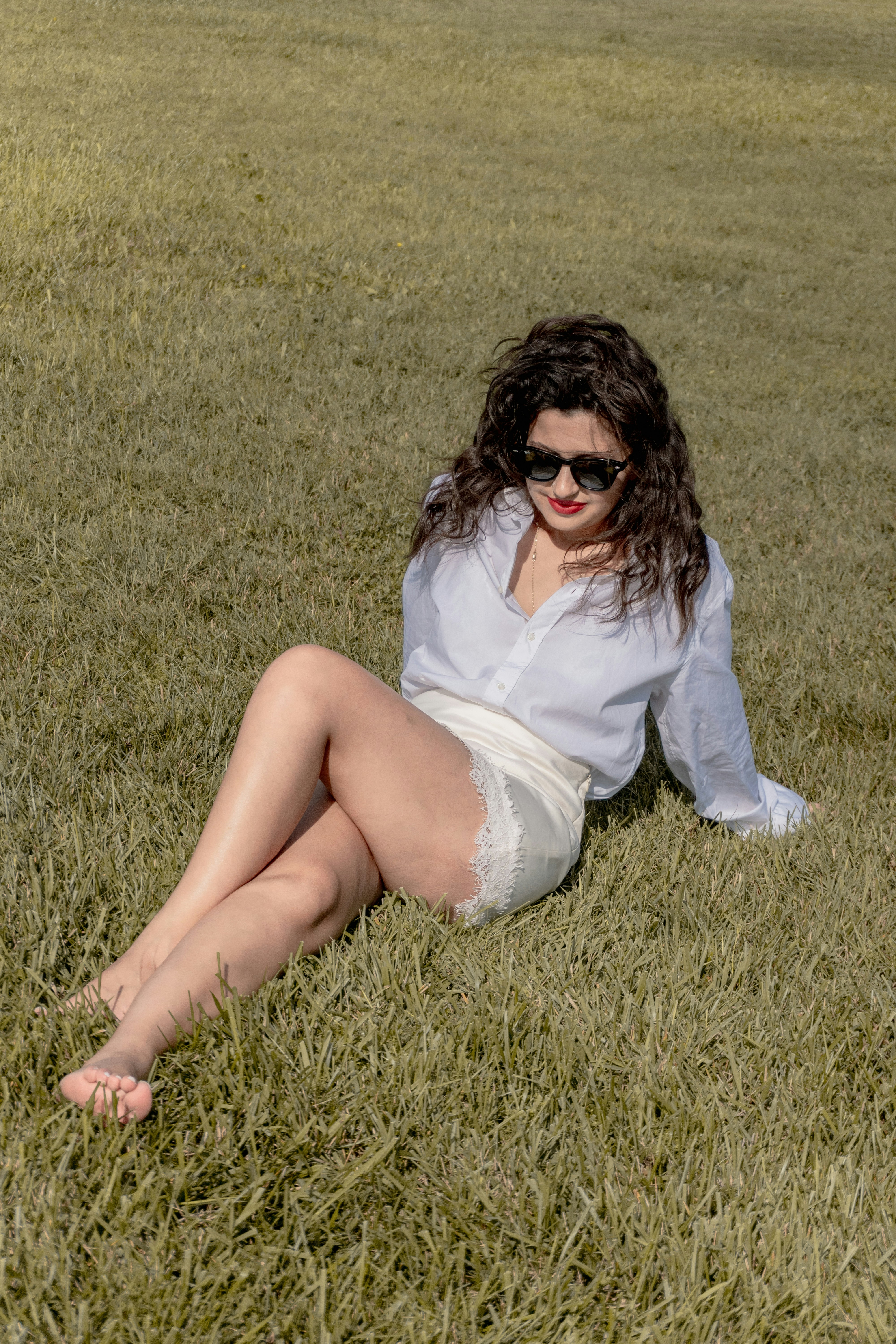 Seated on the grass in a white shirt dress