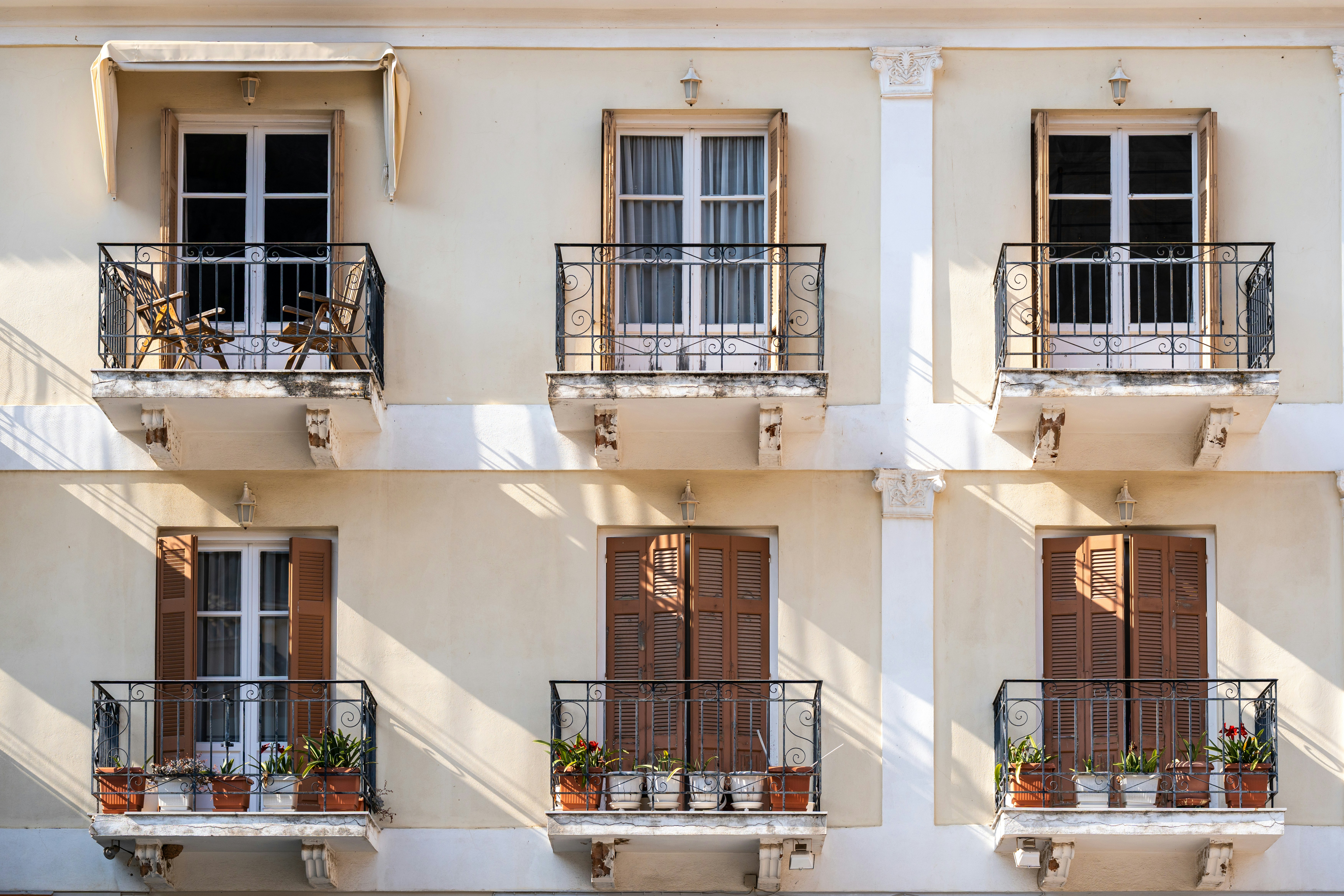 Six balconies with wrought iron railings on a cream colored building facade