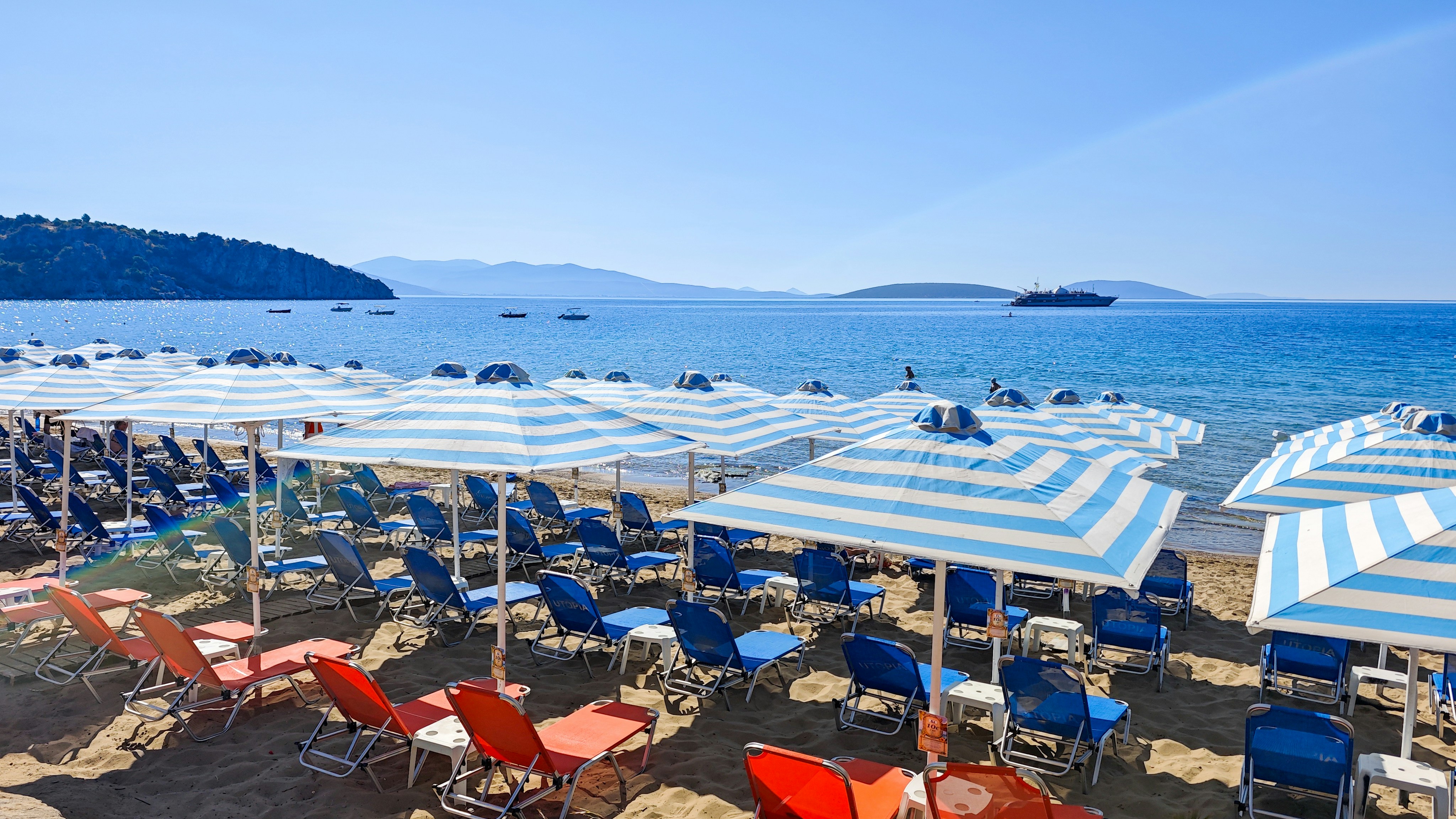 Blue and white striped umbrellas over rows of lounge chairs on a sandy beach
