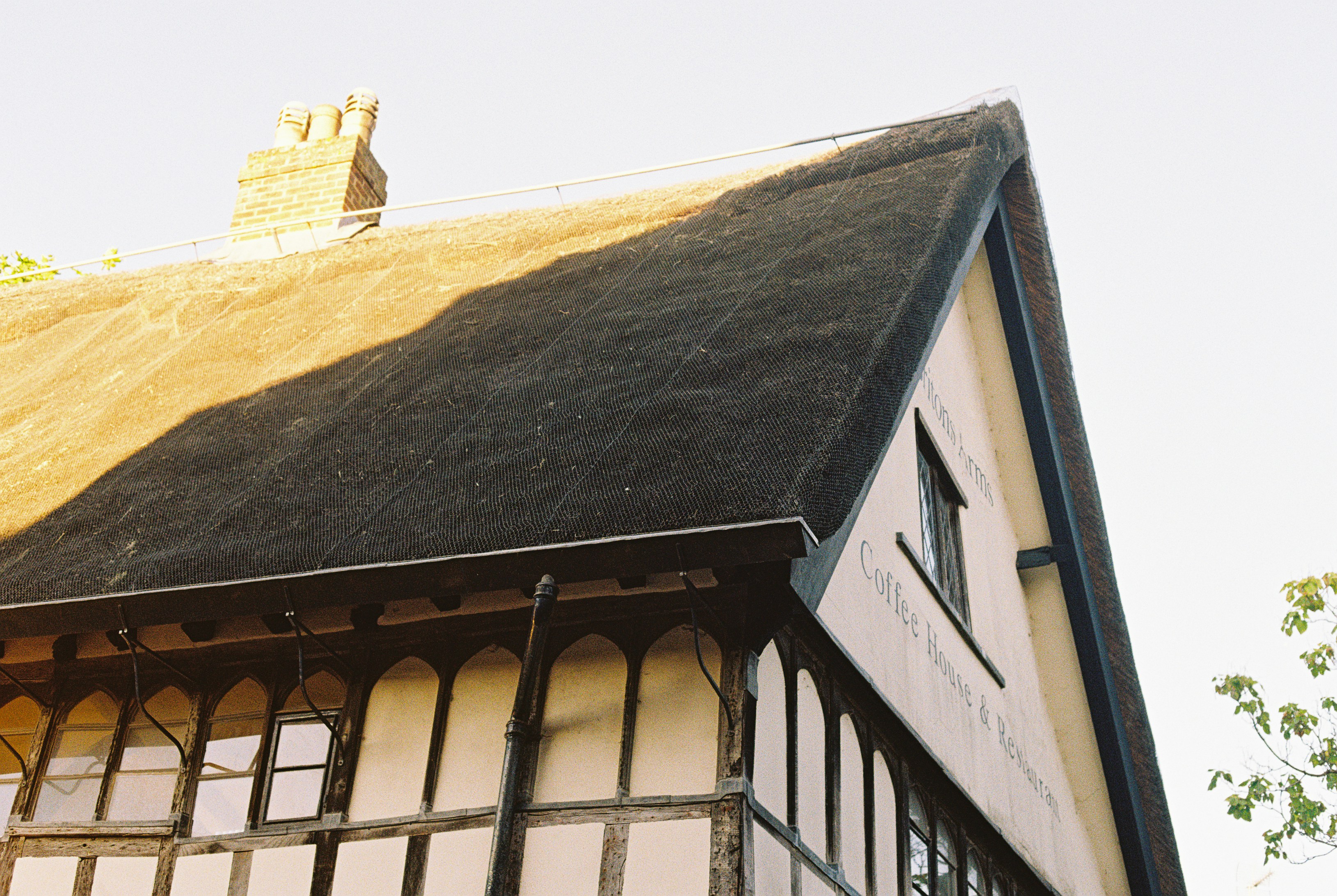 A timber-framed building with a thatched roof and a brick chimney