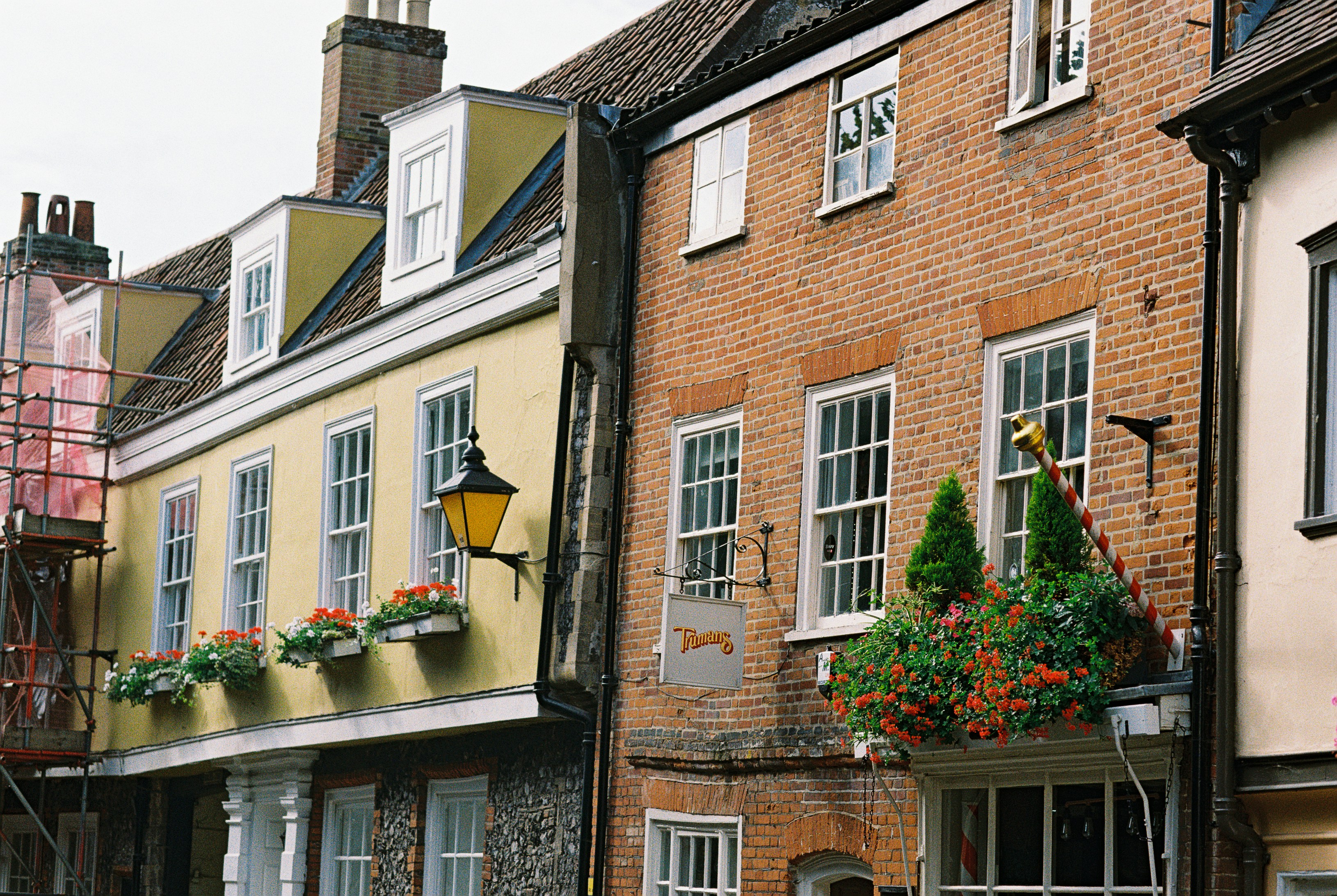 A yellow building and a red brick building with flower boxes and windows