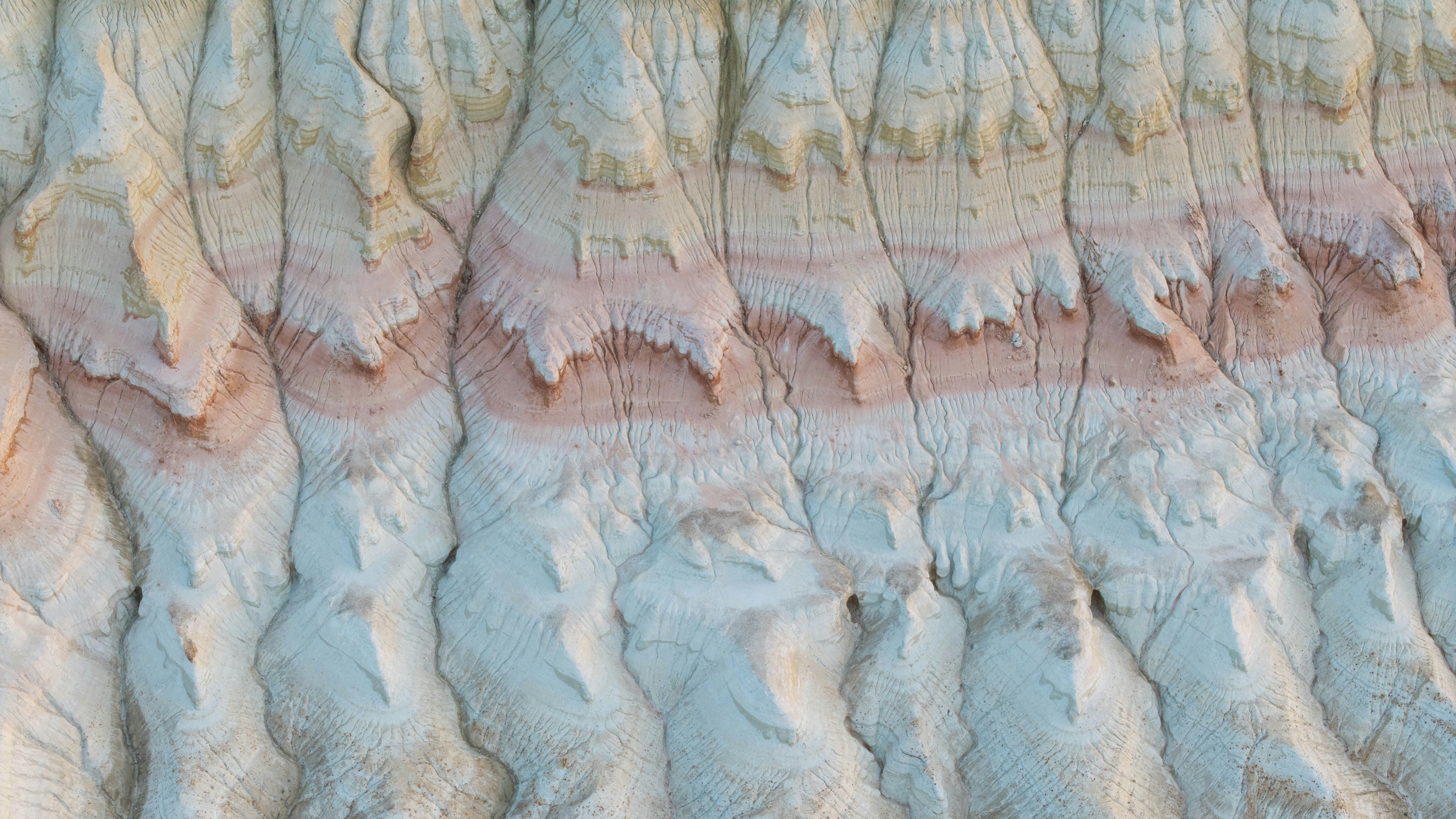 Eroded white and pink clay cliffs with deep vertical fissures and ridges