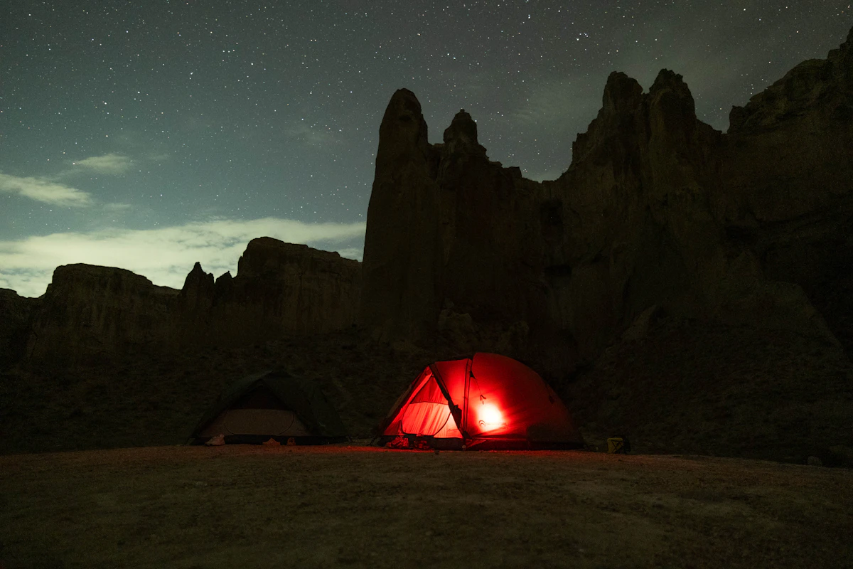 Two tents on a desert floor beneath a starry night sky