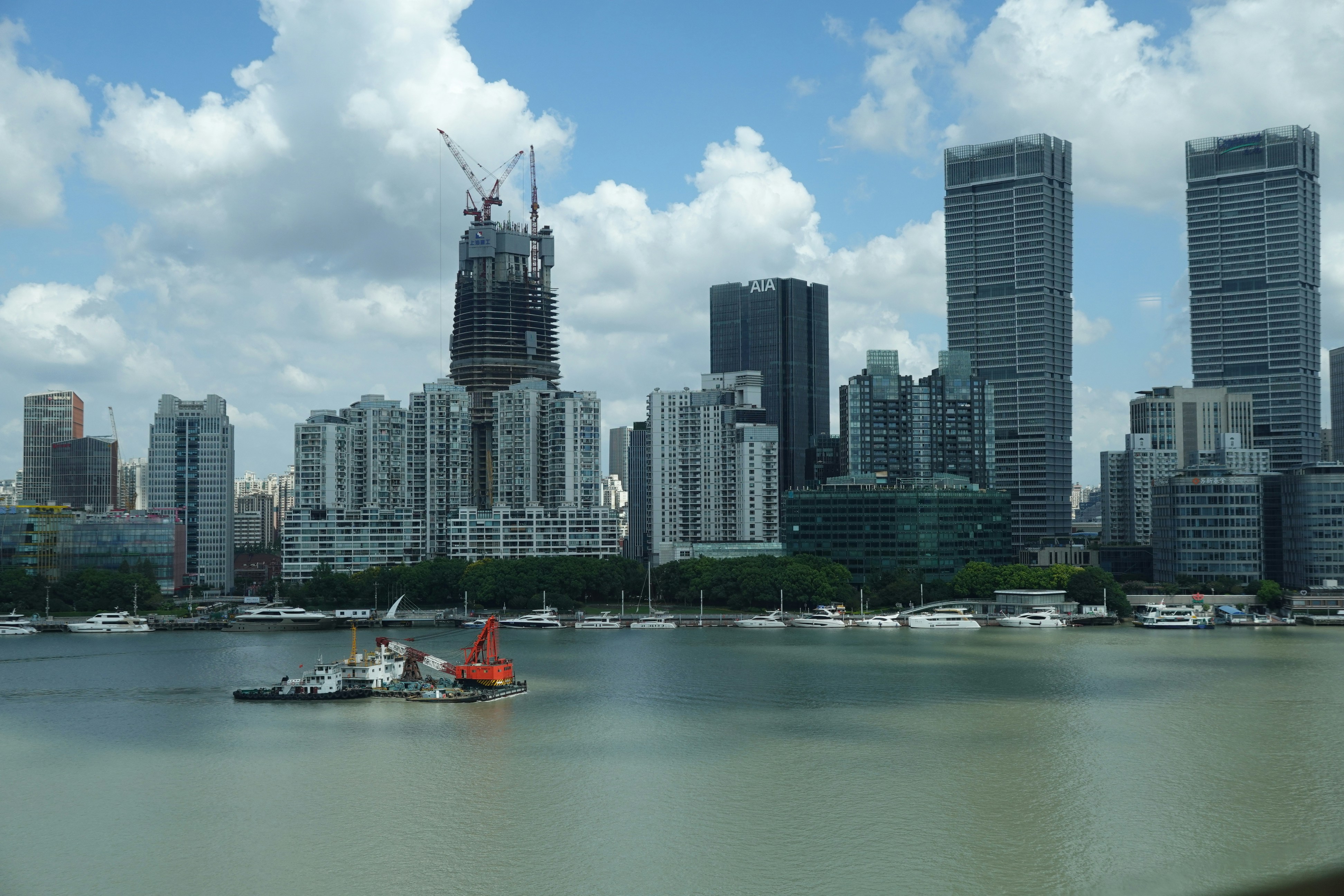 A construction crane on a building under construction near a river with boats